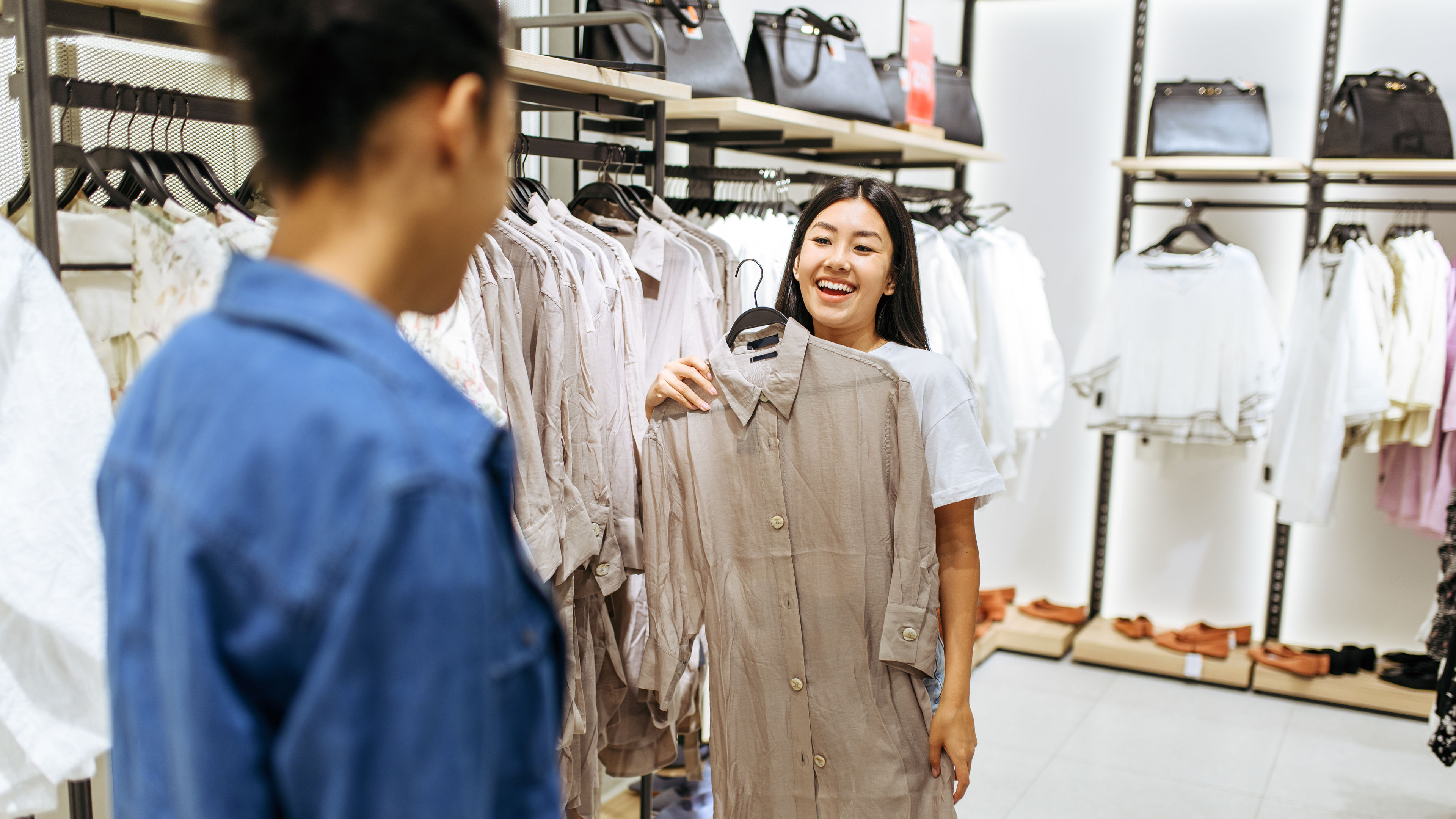 Two happy girls choosing clothes in clothing store.