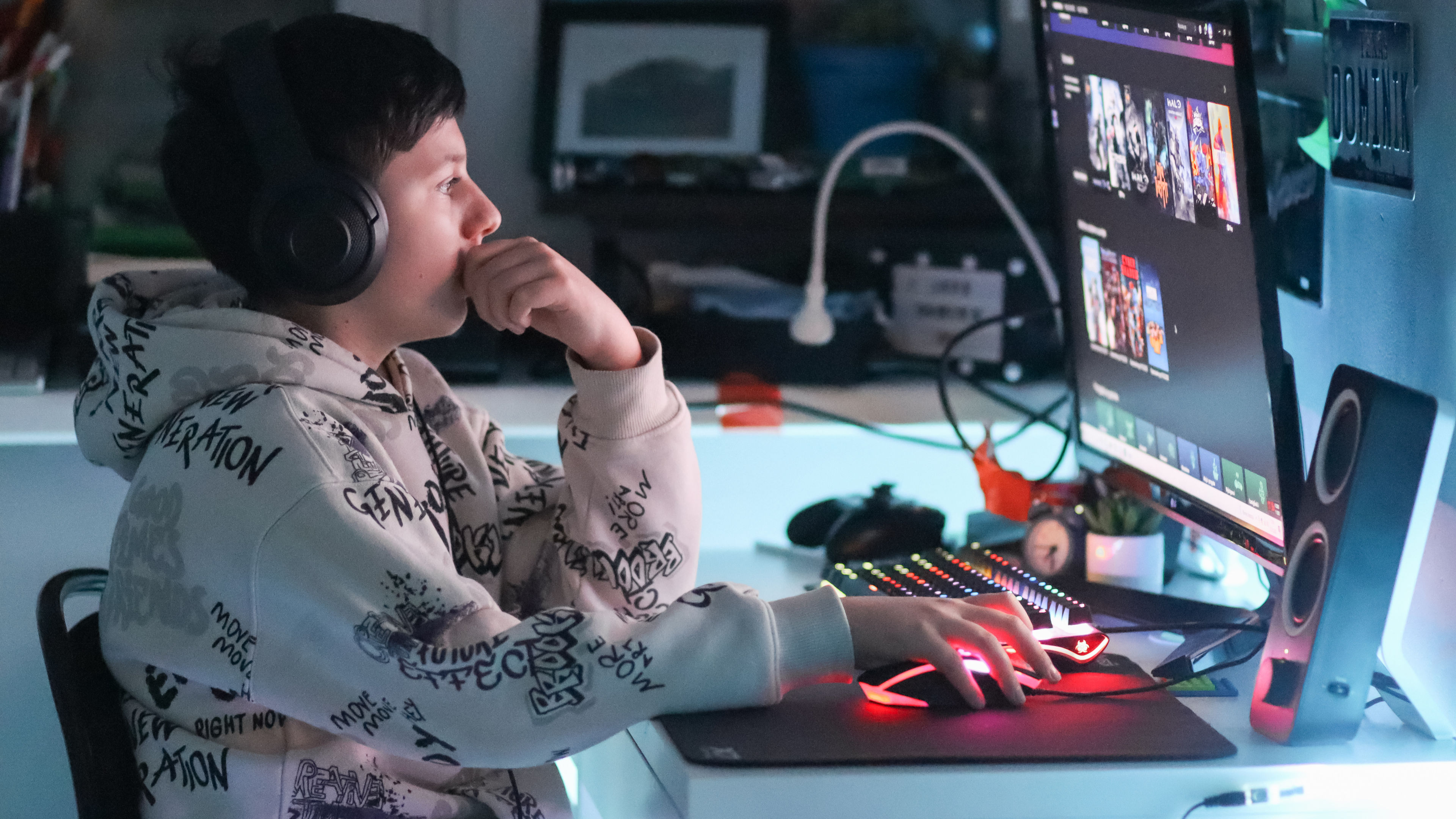 A teenage gamer playing on a computer, surrounded by gaming essentials and apparel.