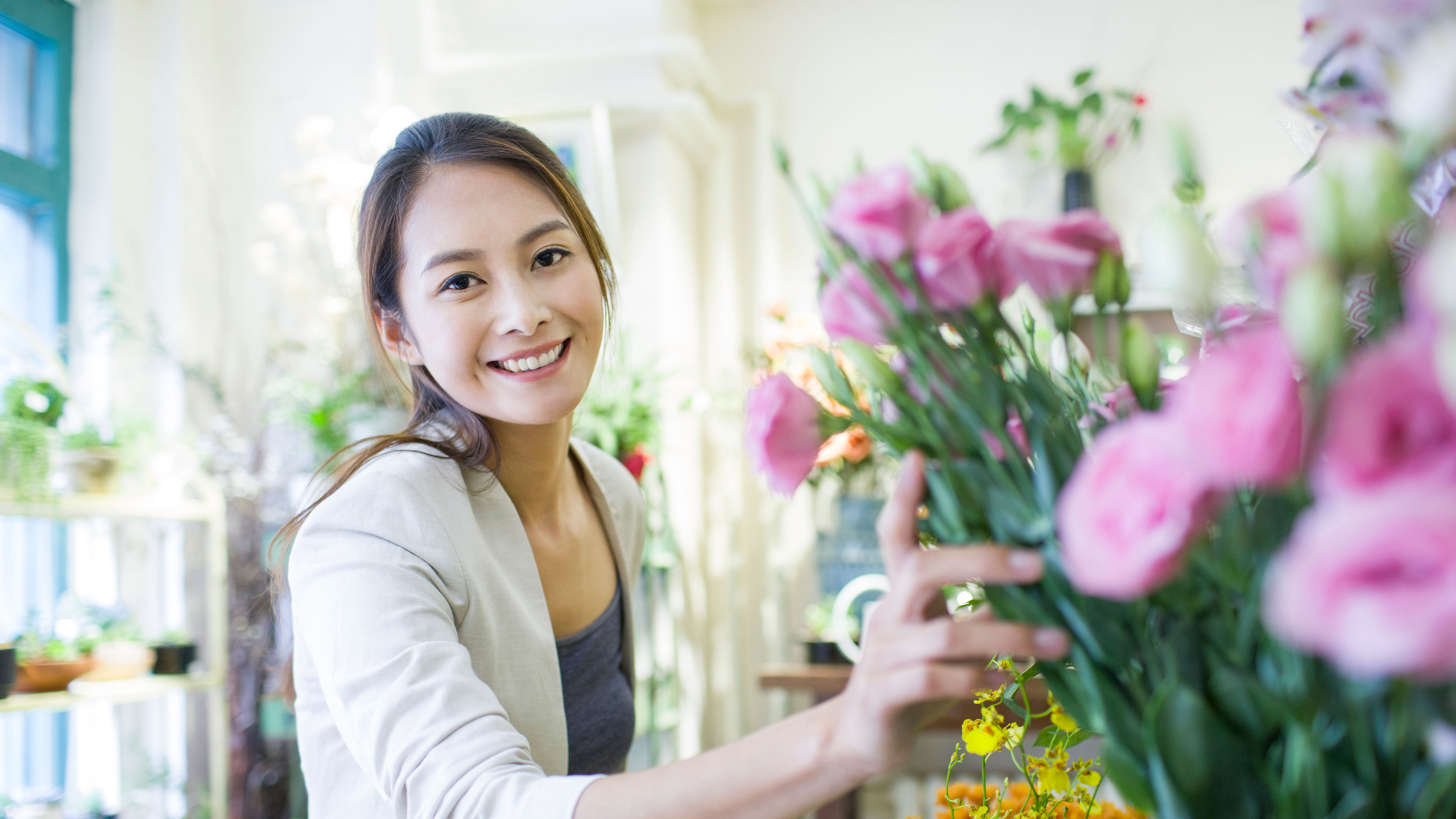 一位靚嘅女人企喺花店度，手度攞住一束花，笑容燦爛。