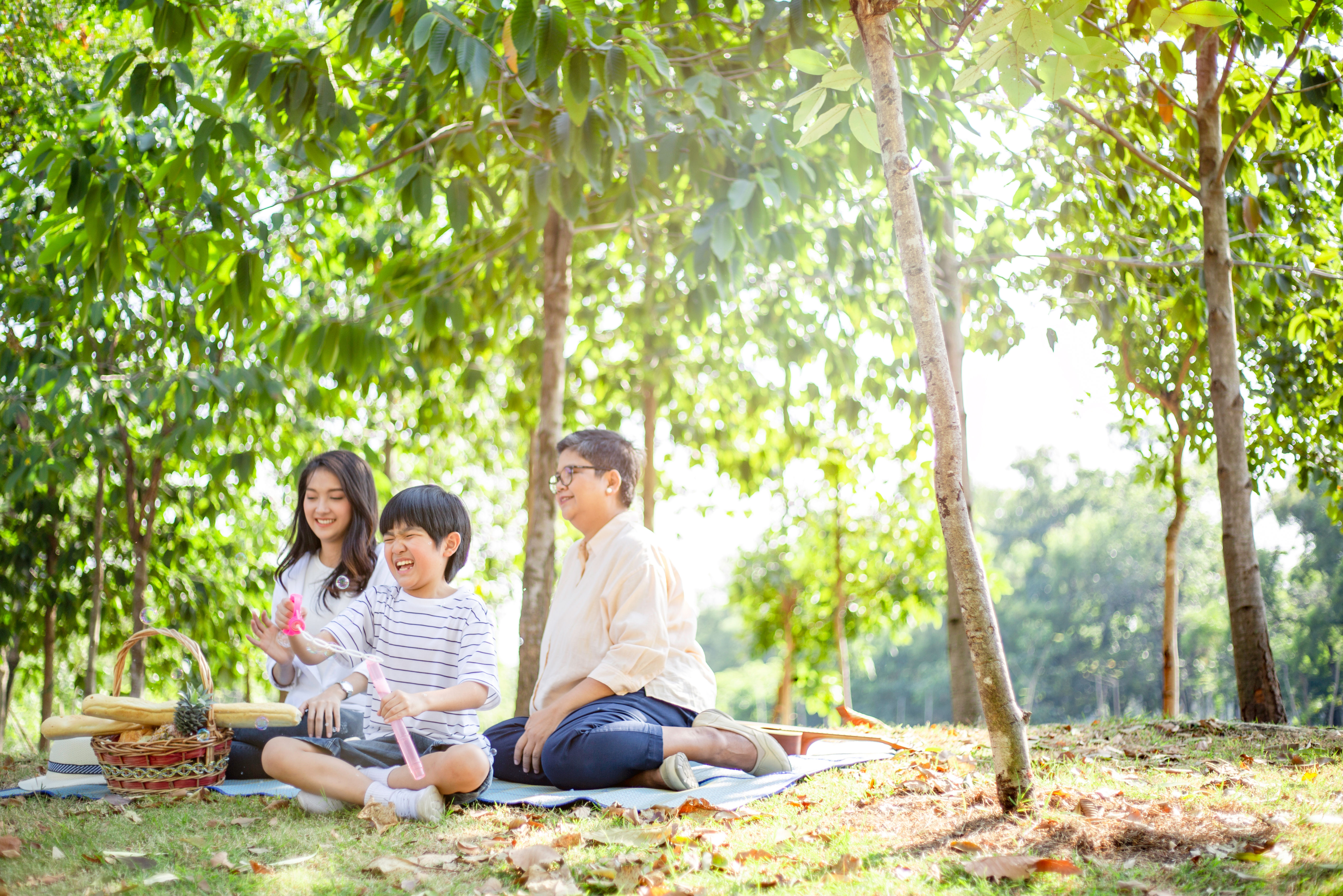 In a serene park, a smiling family sits on a blanket, sharing laughter and snacks 