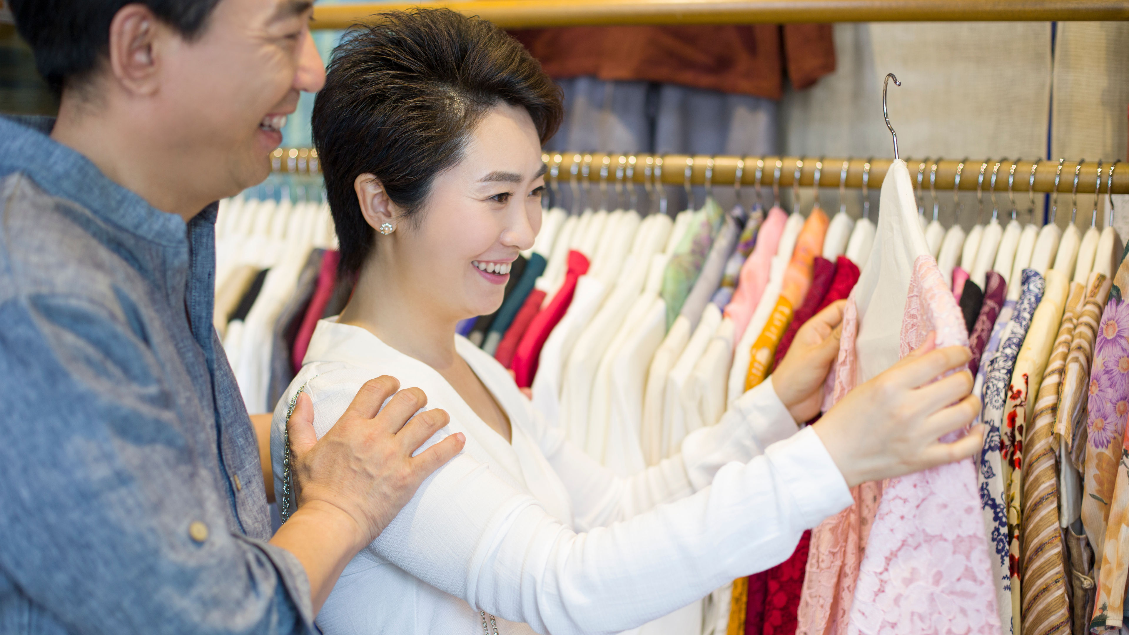 A happy couple shopping for different clothes 