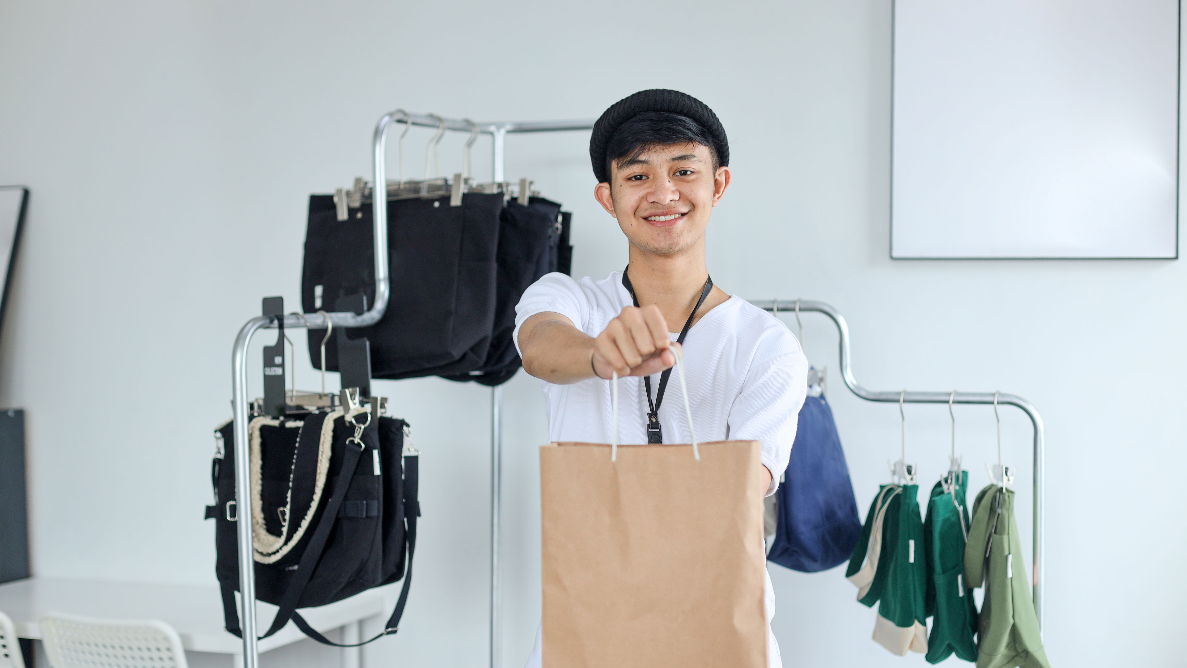 A man serving customer holding paper bag in a clothing store 