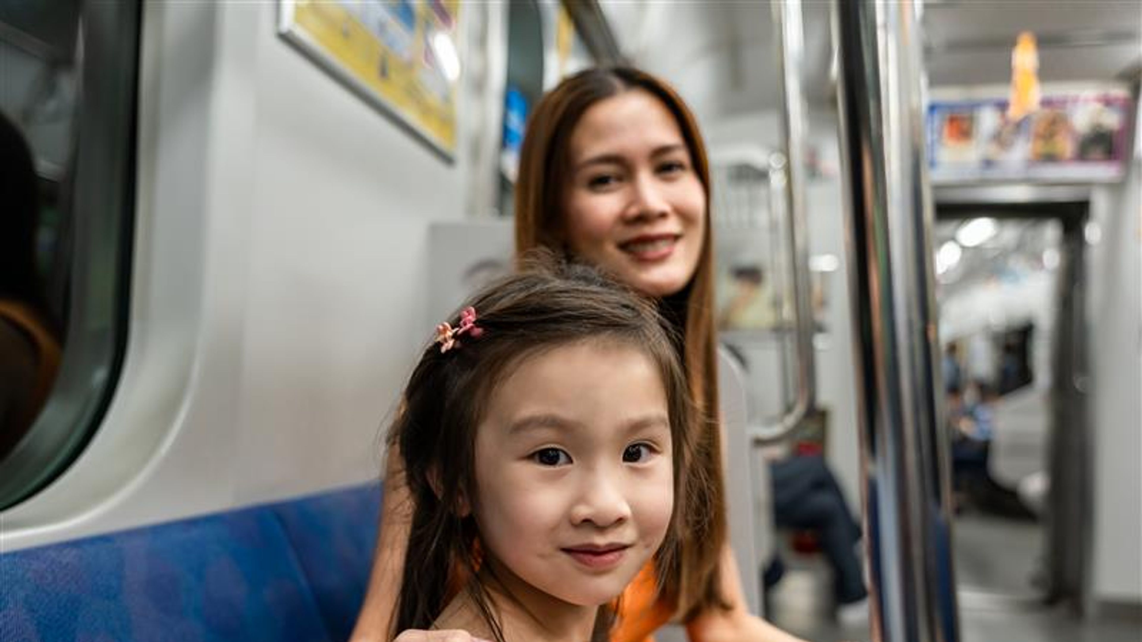 A mom and her daughter are travelling on a train
