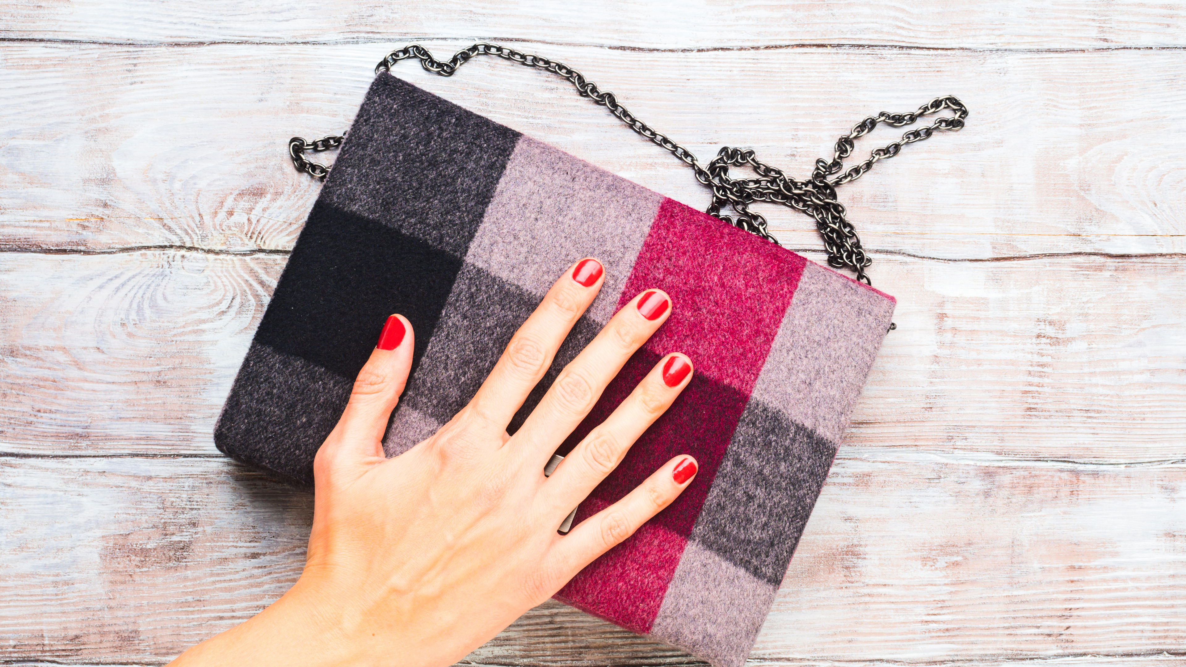 A person touches a plaid handbag 