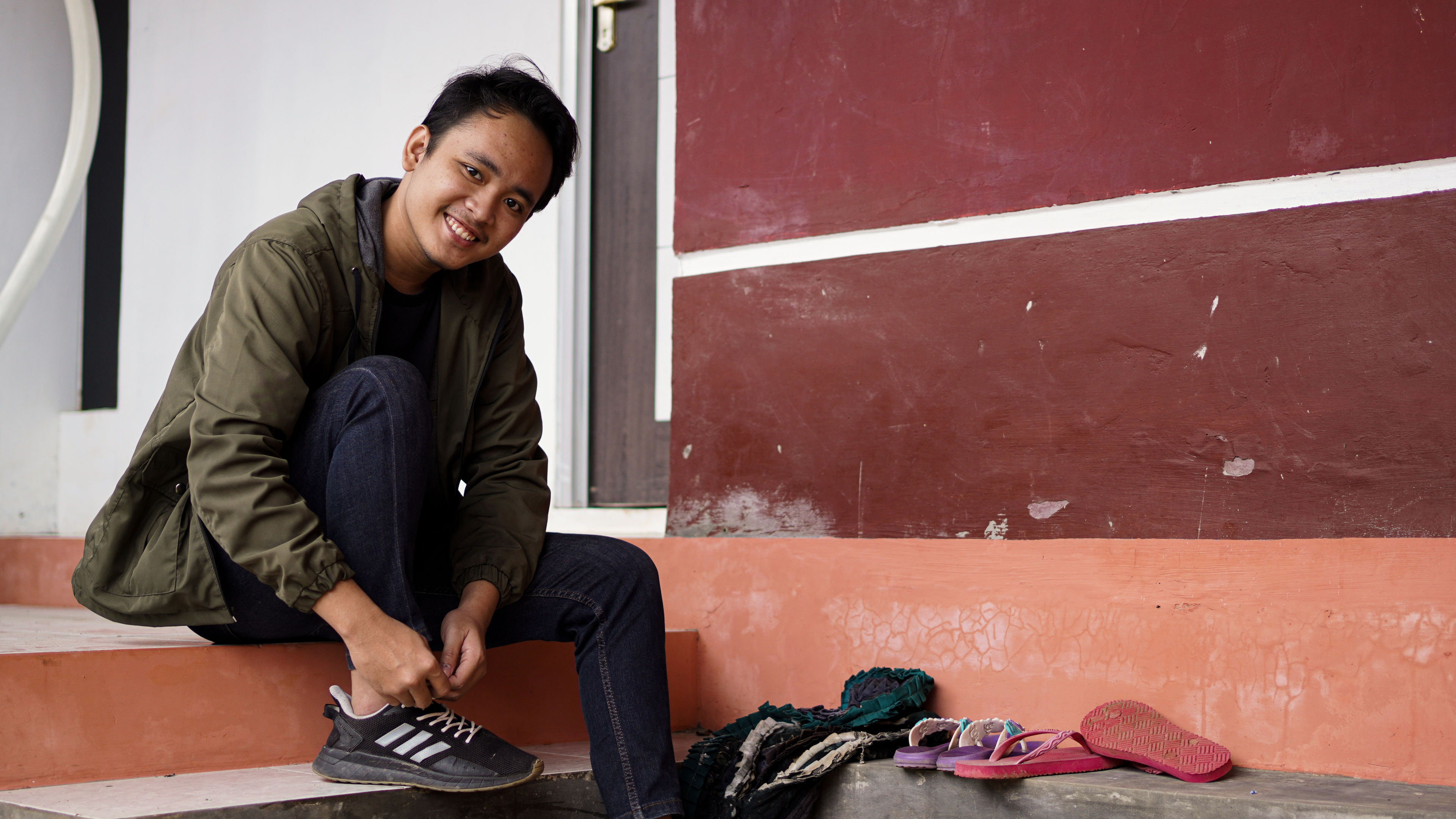 A portrait of a young man sitting in a new house wearing shoes