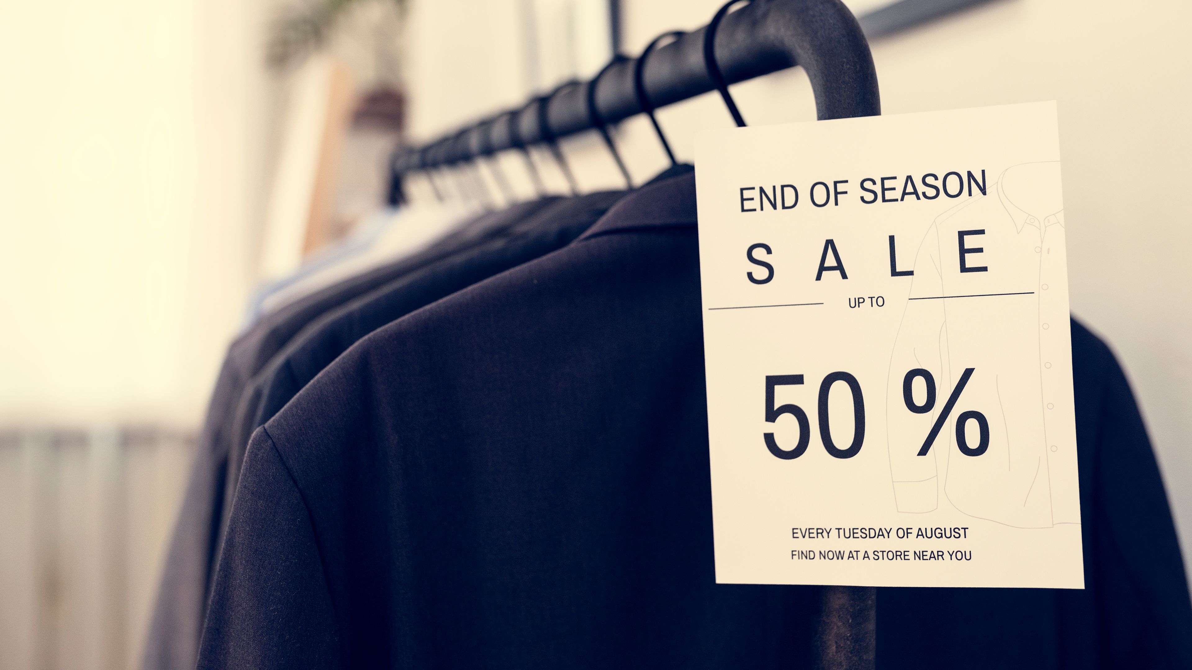 The neatly arranged rack of clothes with the prominent sale sign 
