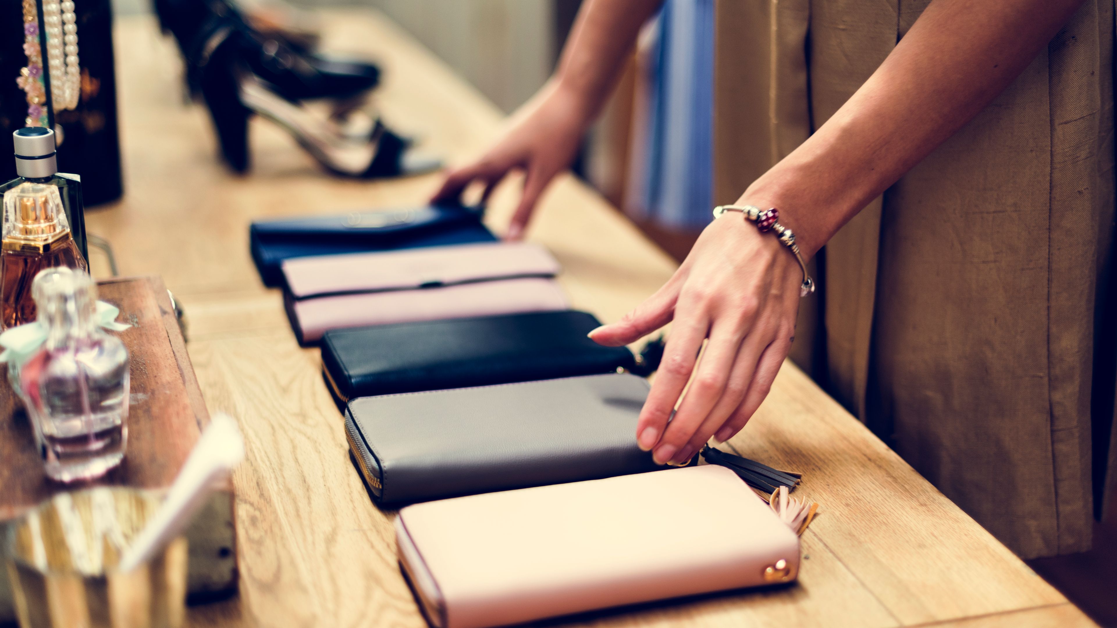 A woman arranges a selection of sleek purses on a boutique table 