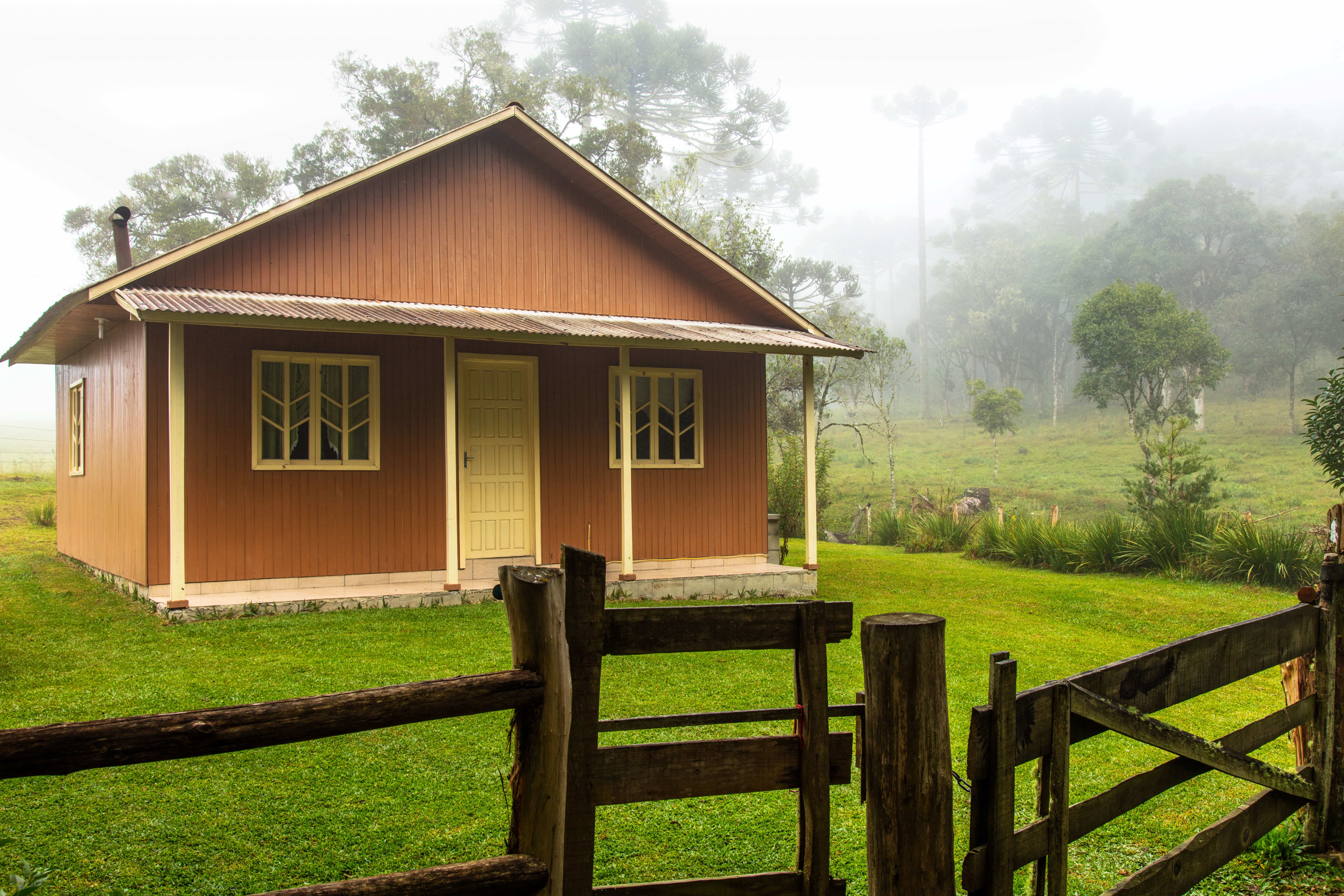 A small wooden guesthouse is situated in a lush, green countryside. 