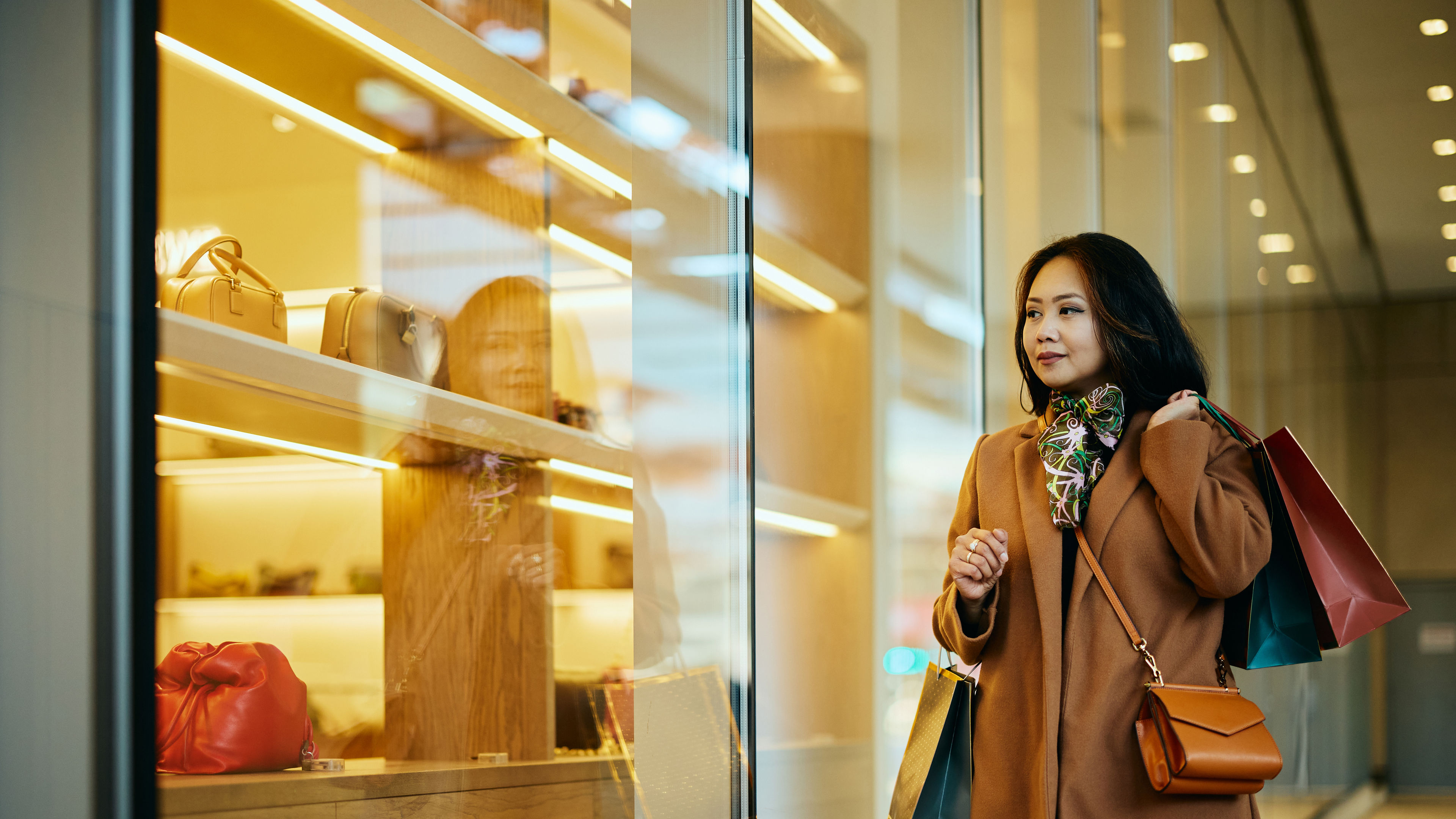 An elegant woman stops to admire luxurious designer handbags 