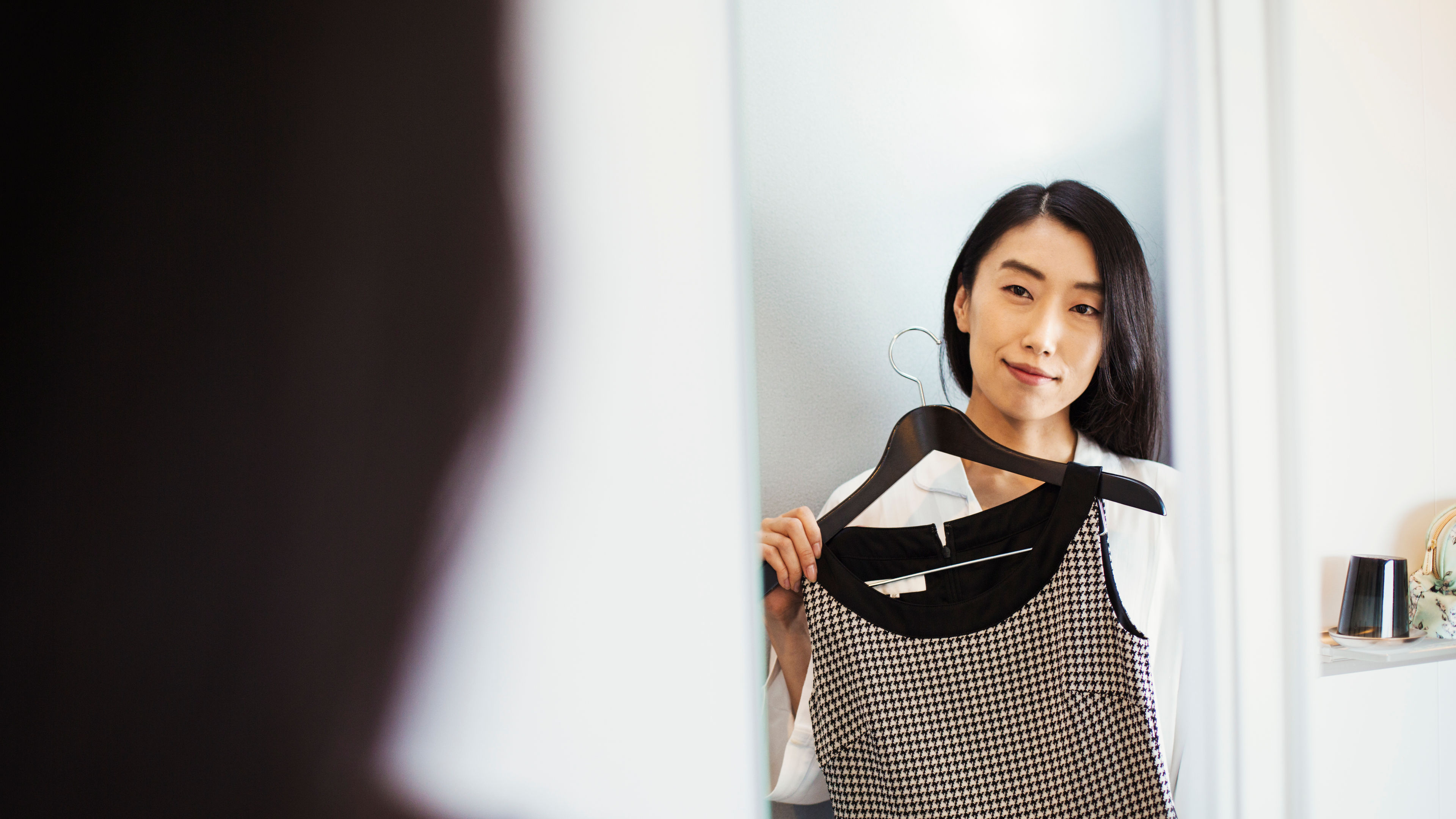 A businesswoman preparing for work, dressing, holding a dress on a hanger. 