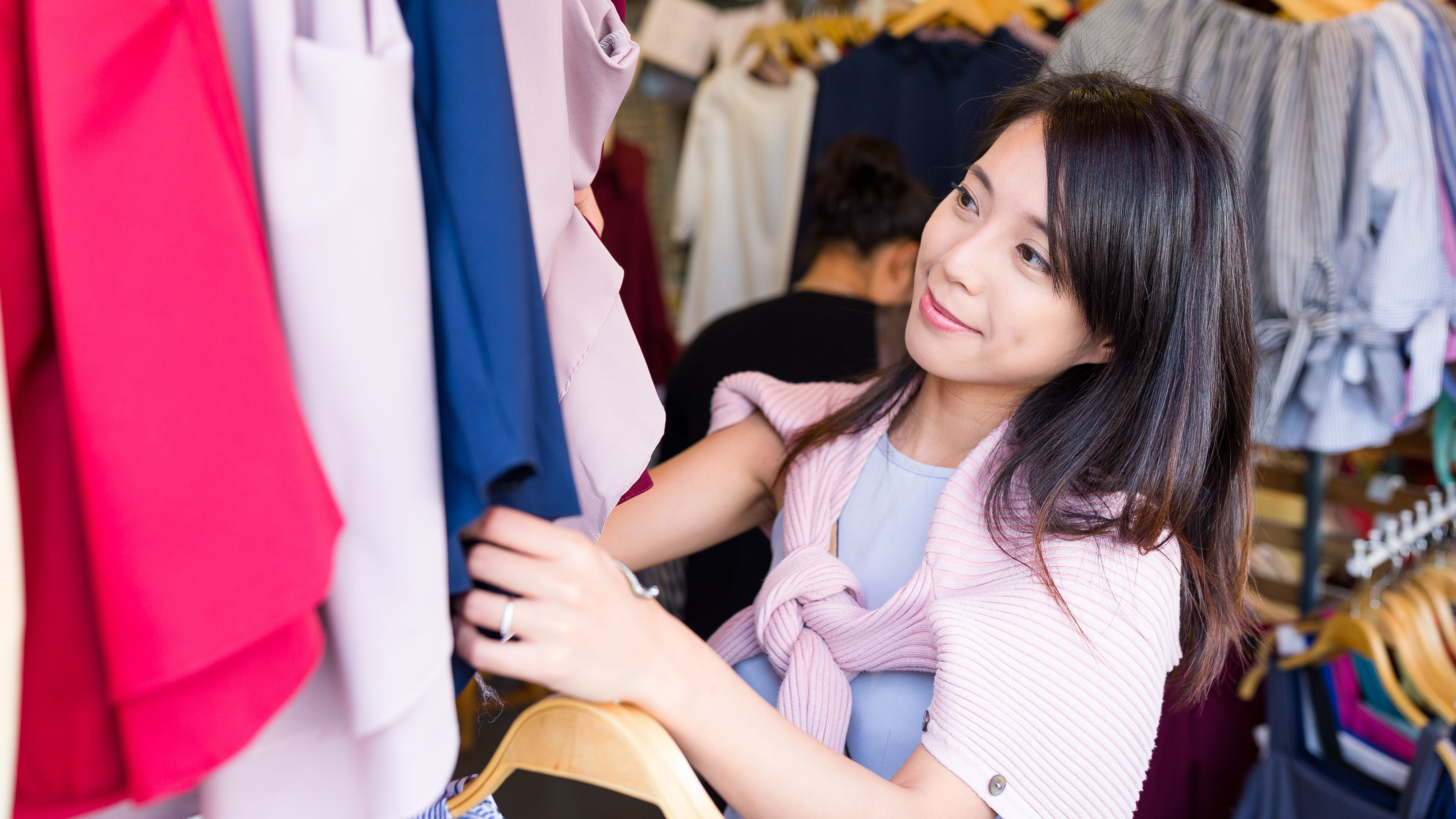 A smiling woman selecting clothes in a shopping mall 
