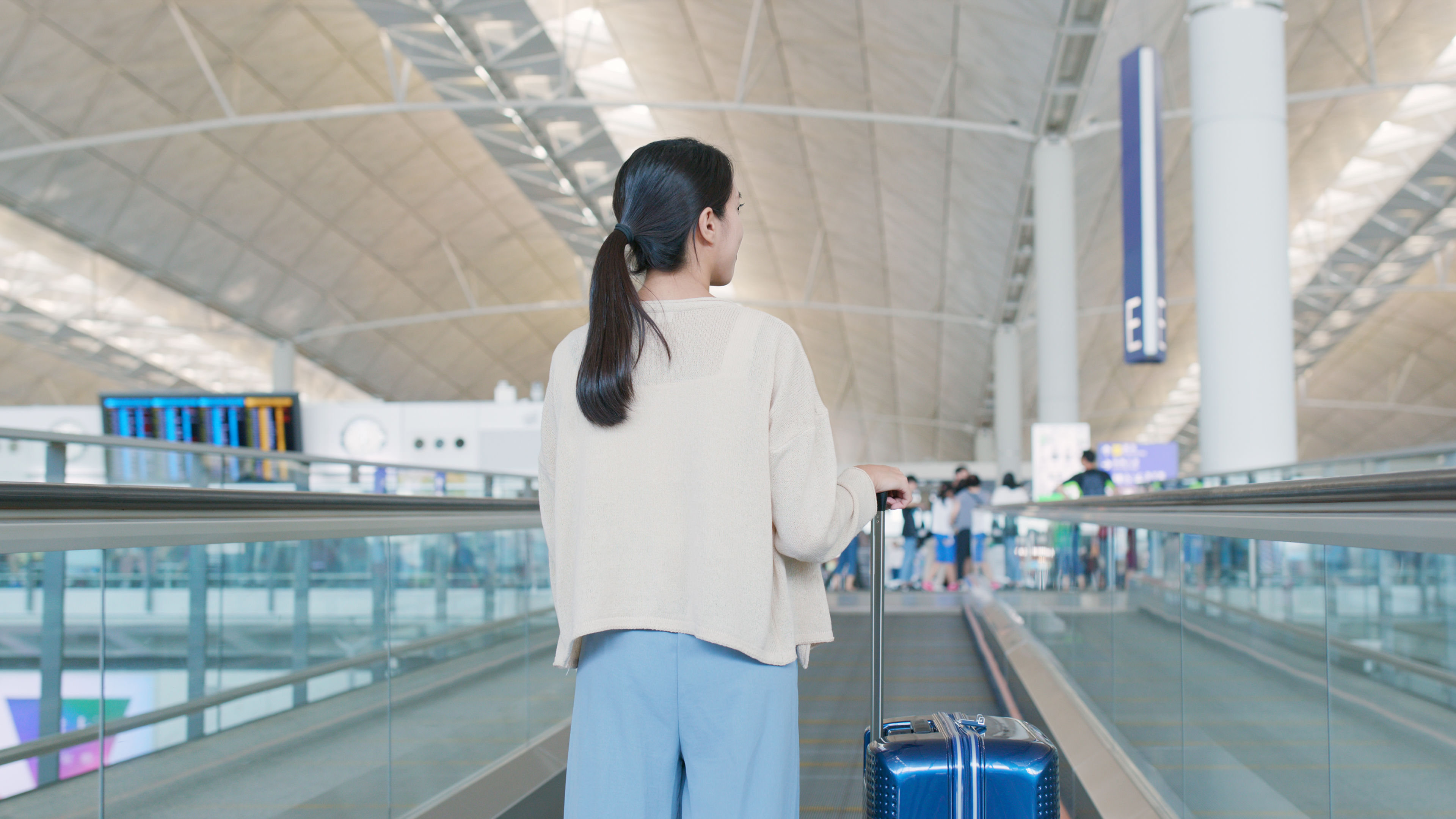 A woman walking in the airport with her luggages. 