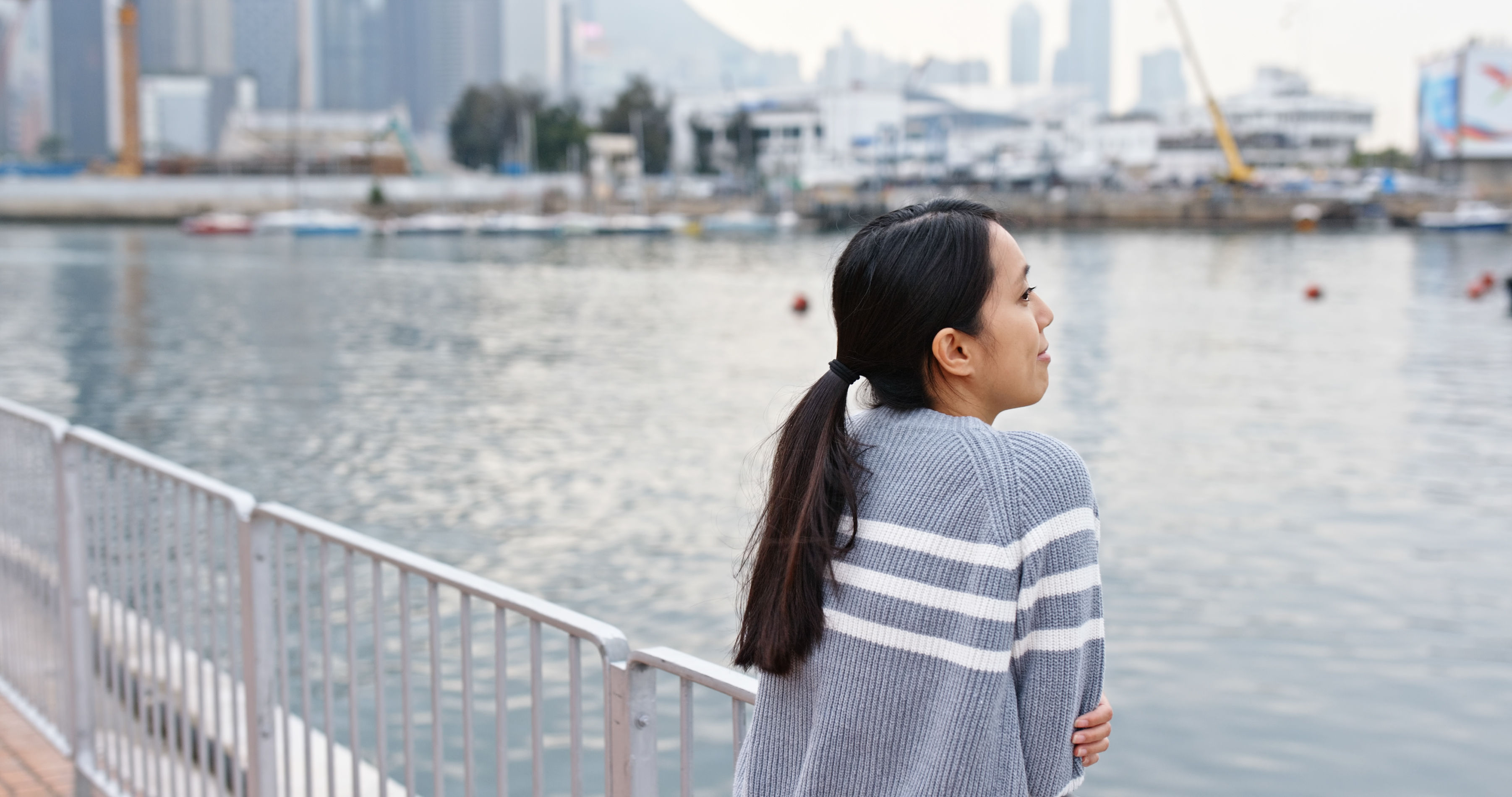 A woman wears stylish clothing and looking at the sea 