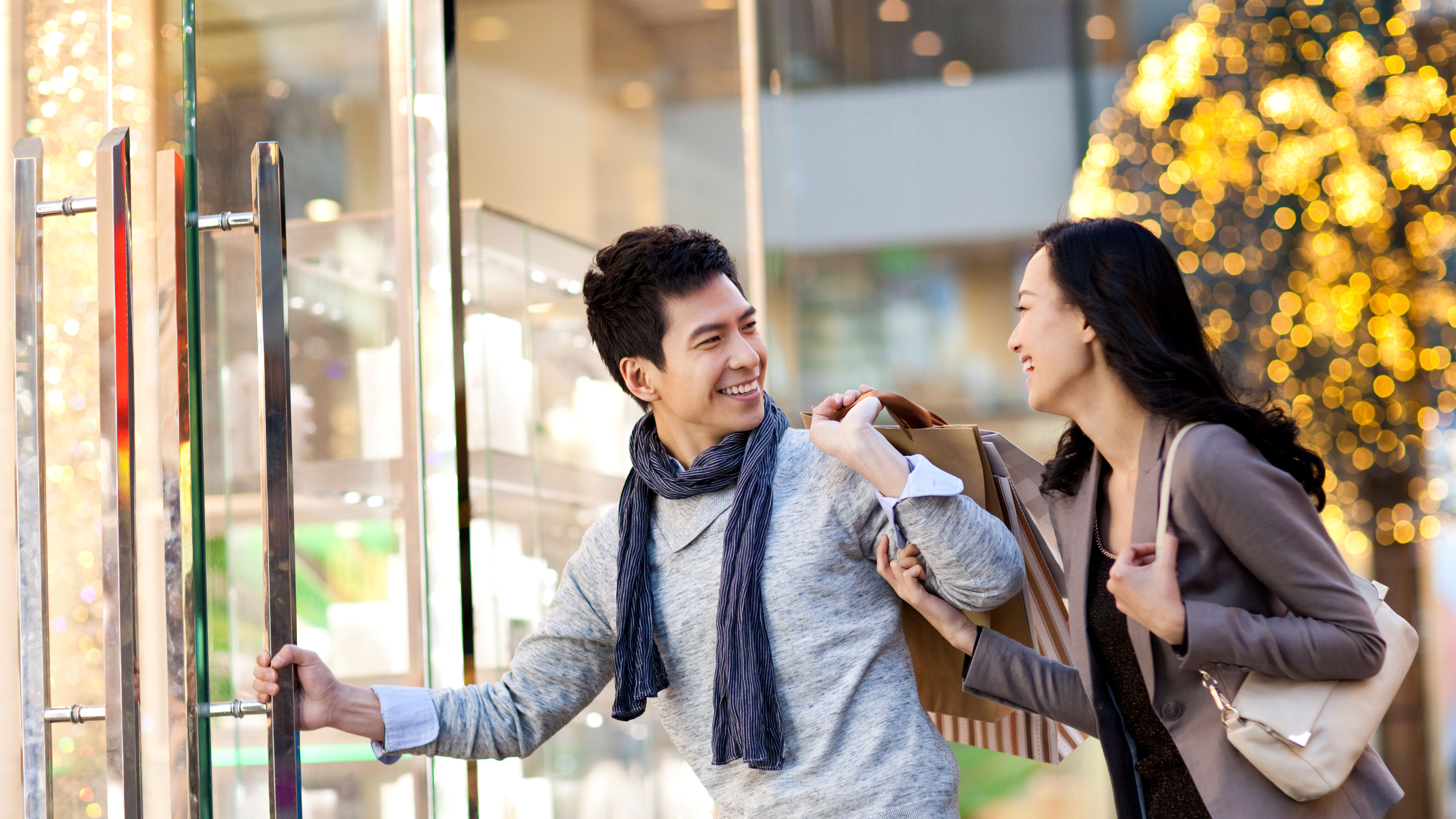 Sweet young Chinese couple entering a shopping mall 