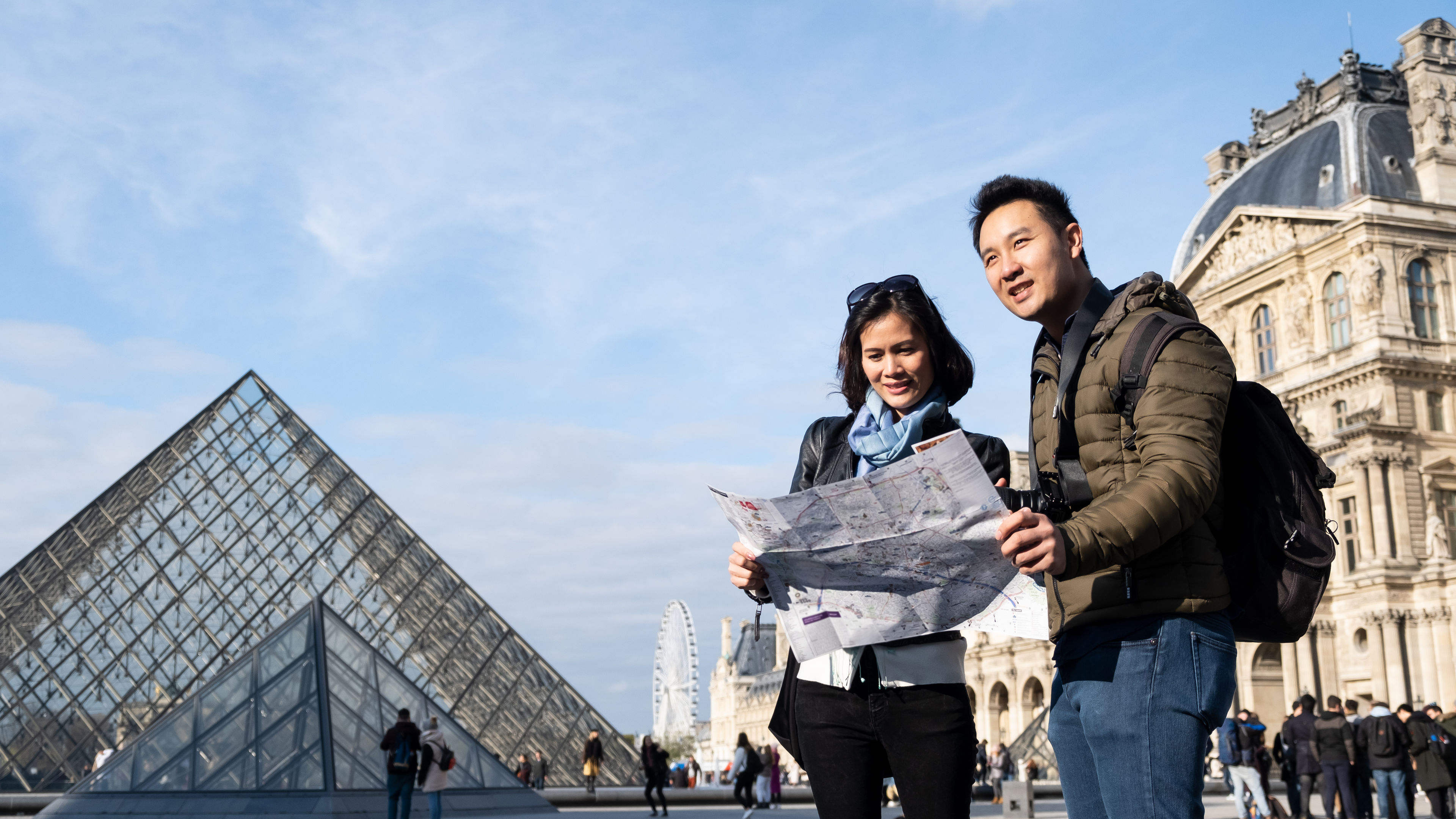 A young couple of Asian travelers is holding a city map