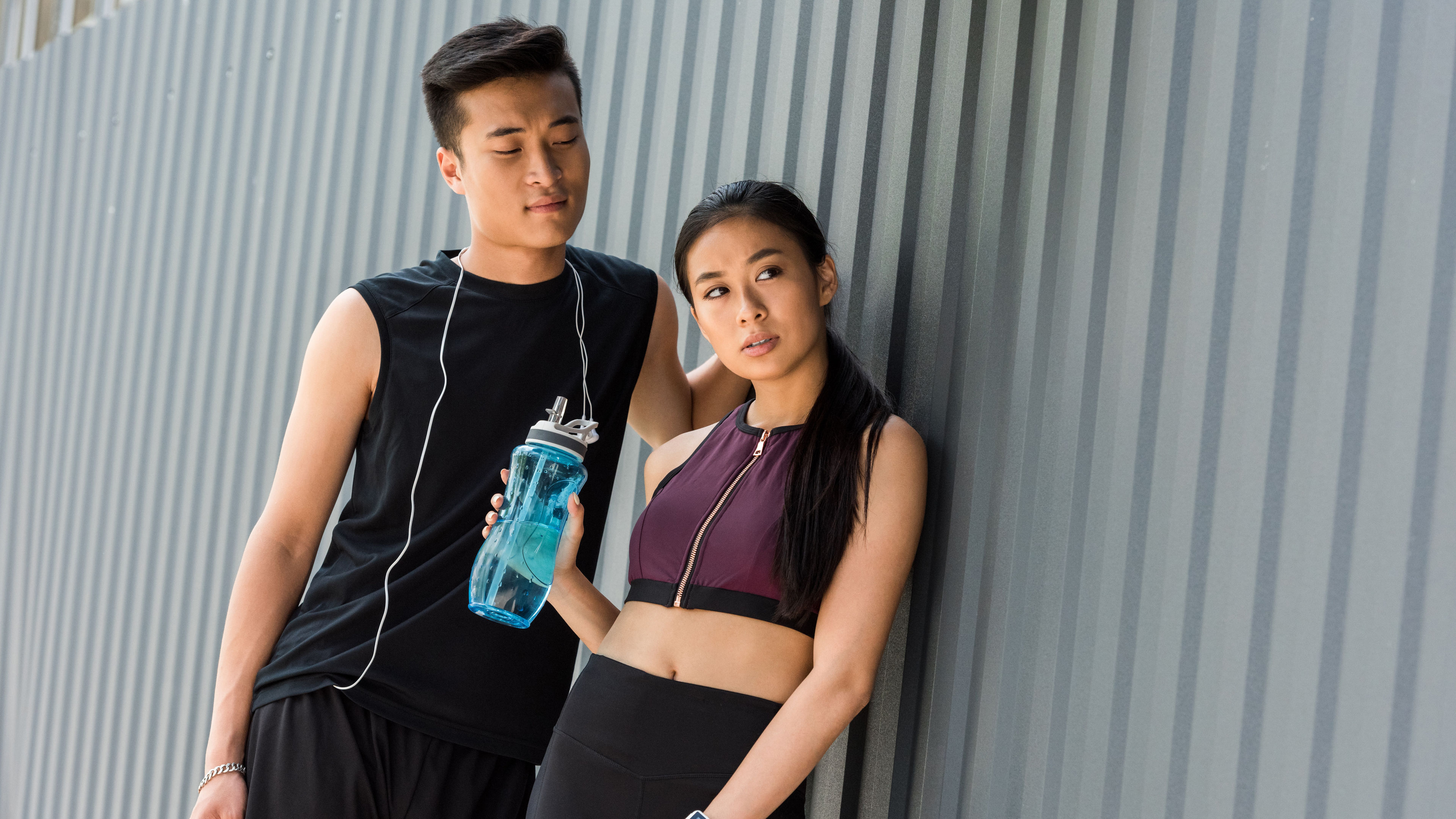 A young man and woman are leaning against a wall