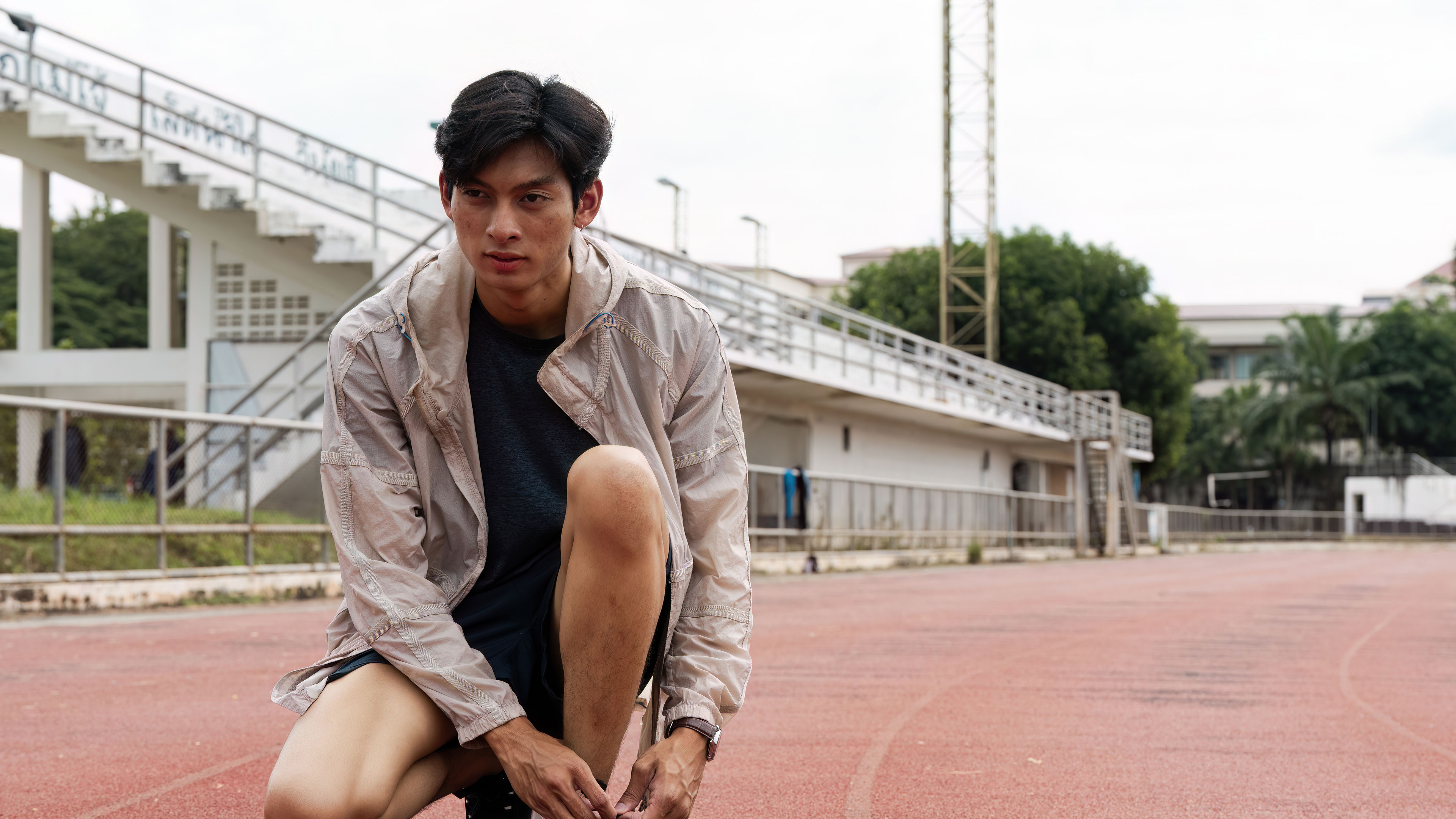 A young man ties his shoelaces on a track