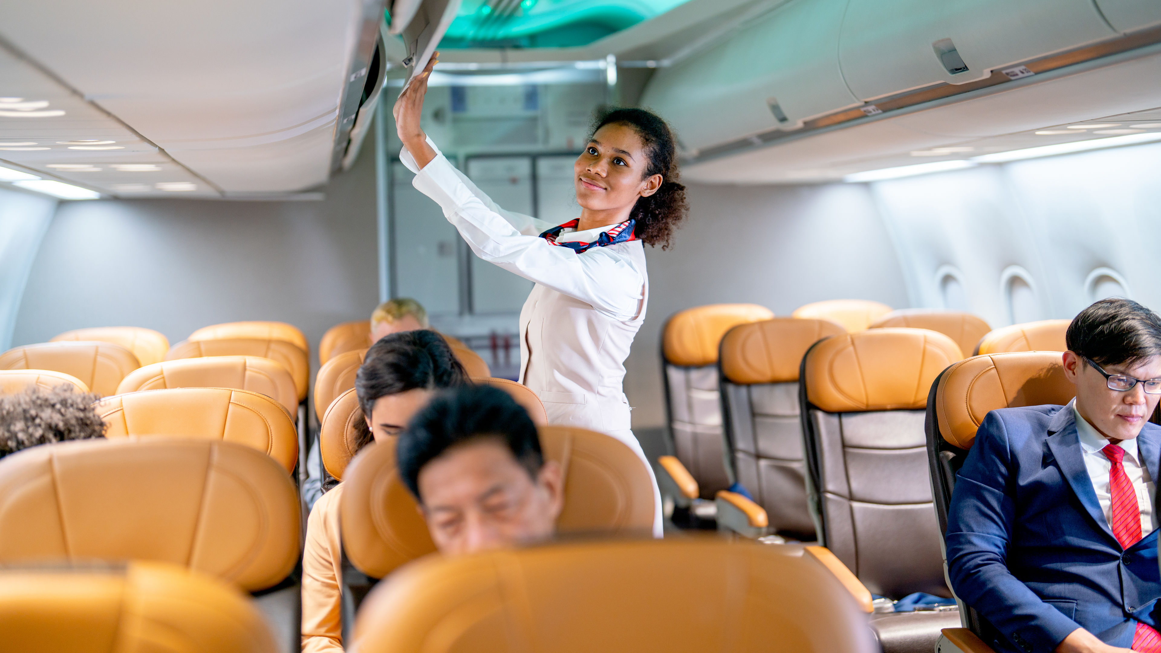 Air hostess walk to close luggage compartment of airplane before take off and bring the passenger