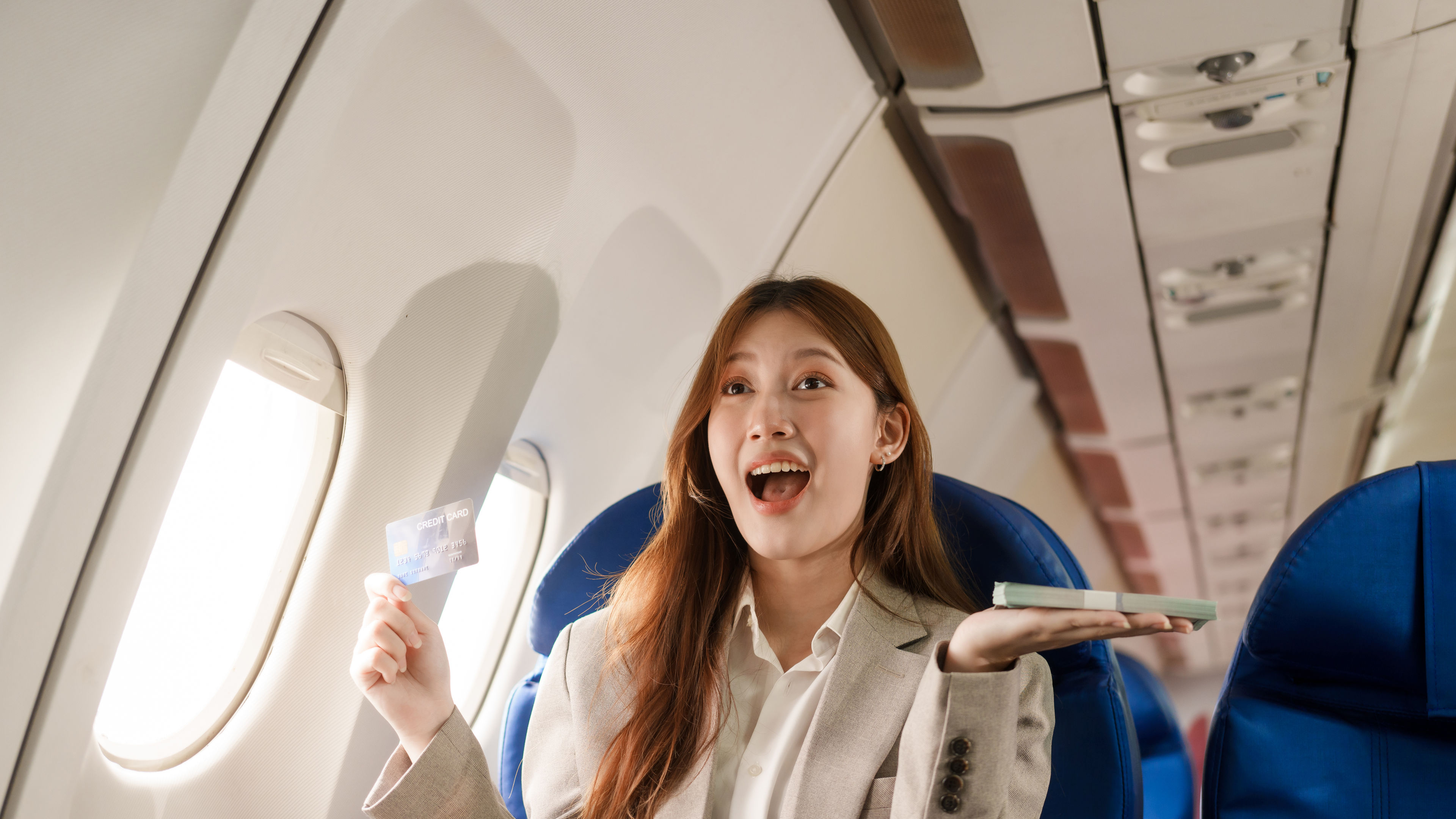An Asian businesswoman travels abroad plane, sitting near window.reads a book uses her computer
