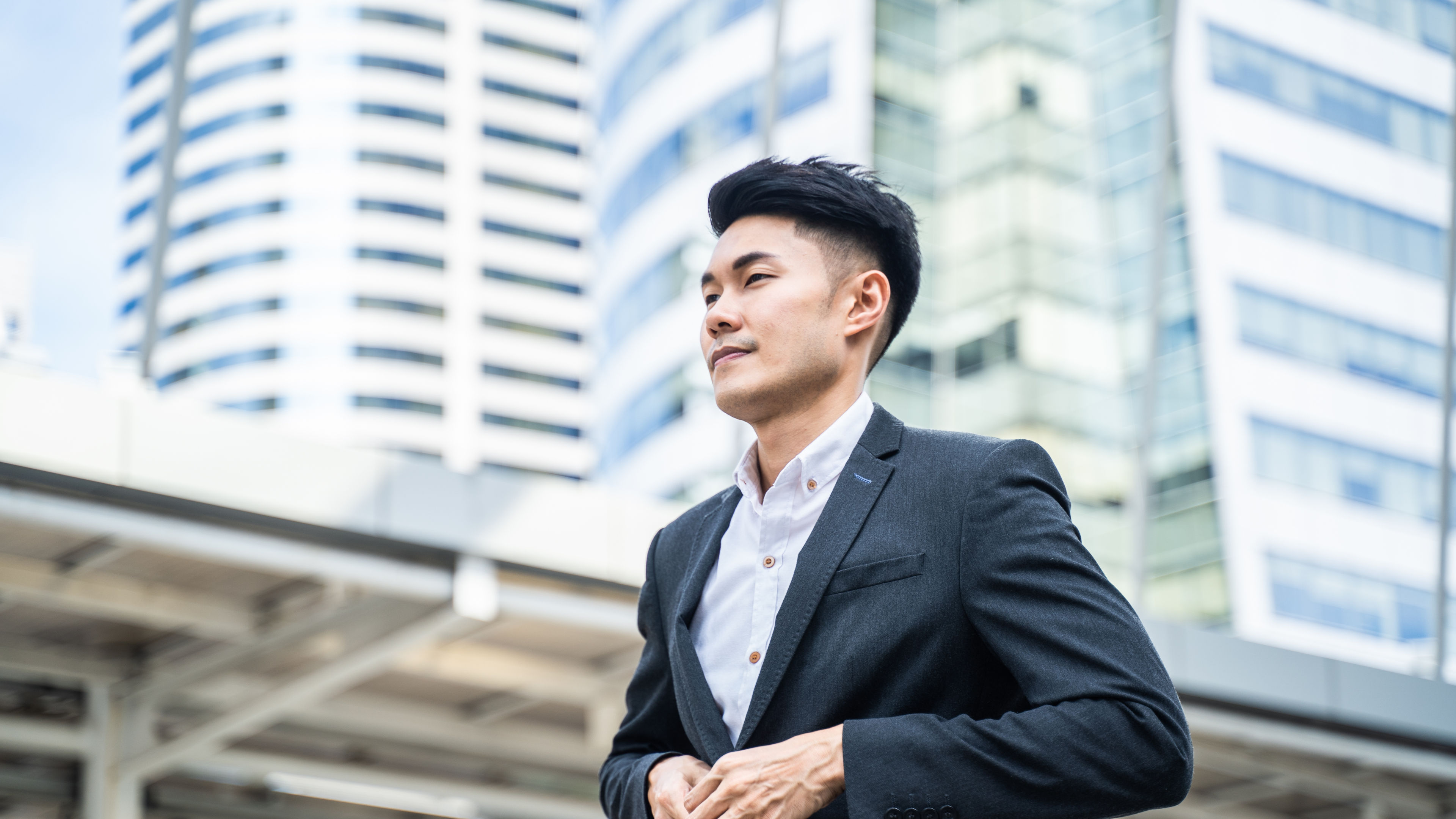 An attractive young Asian office worker stands outdoors in the city