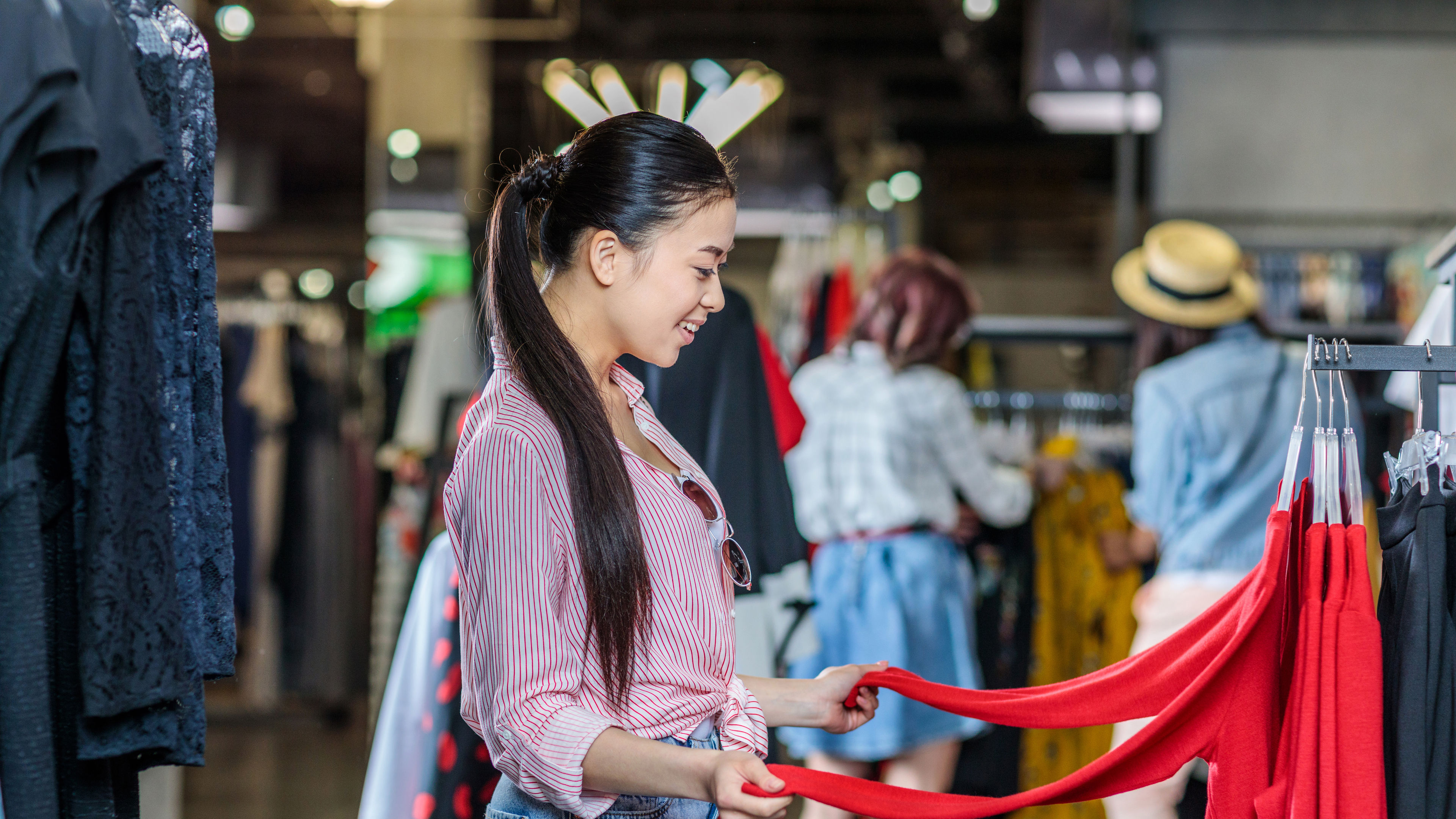 An Asian hipster girl browsing clothes in a trendy shopping mall. 