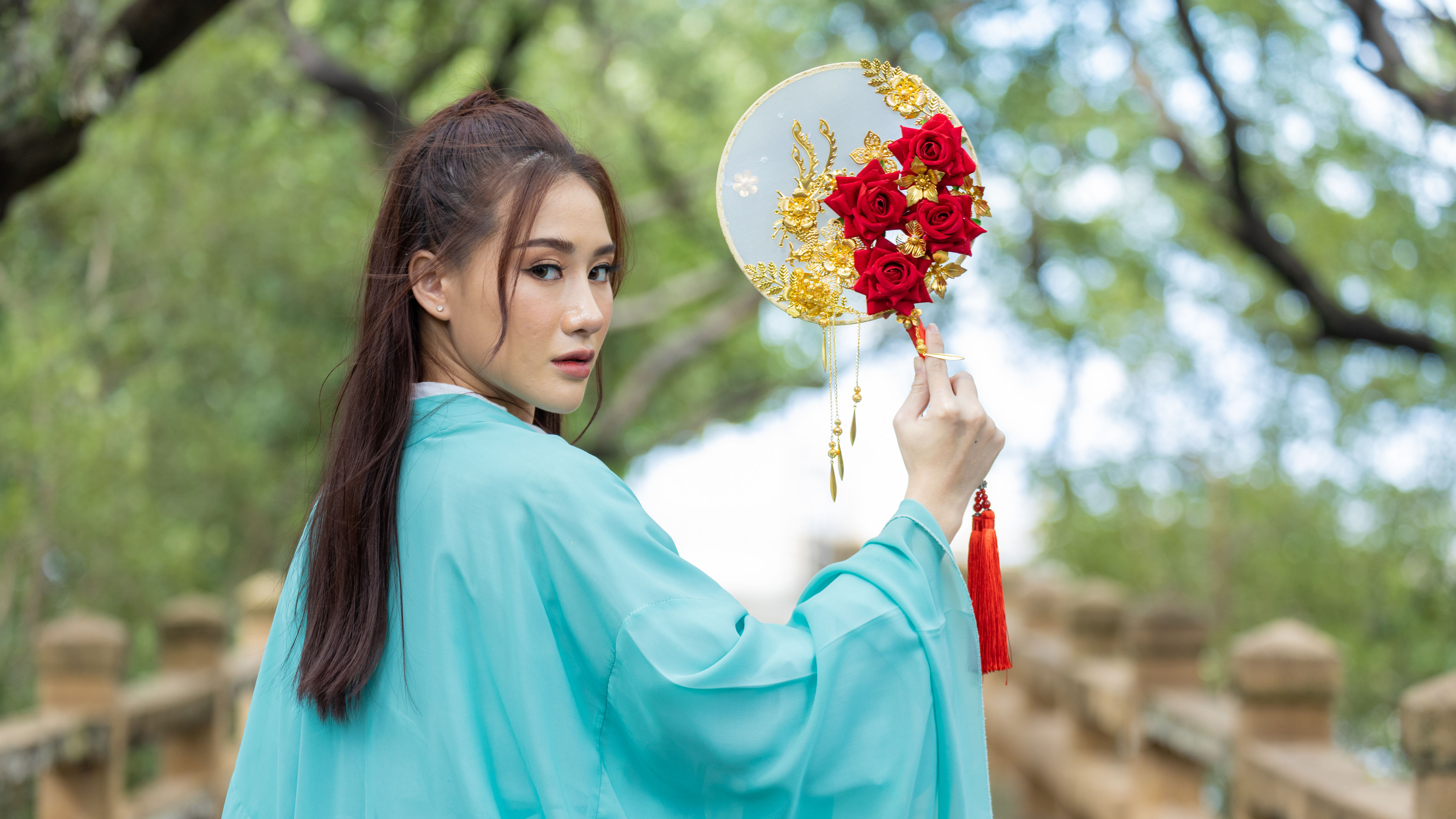 Young beautiful Asian woman dressed in ancient Chinese warrior style with ancient fan 