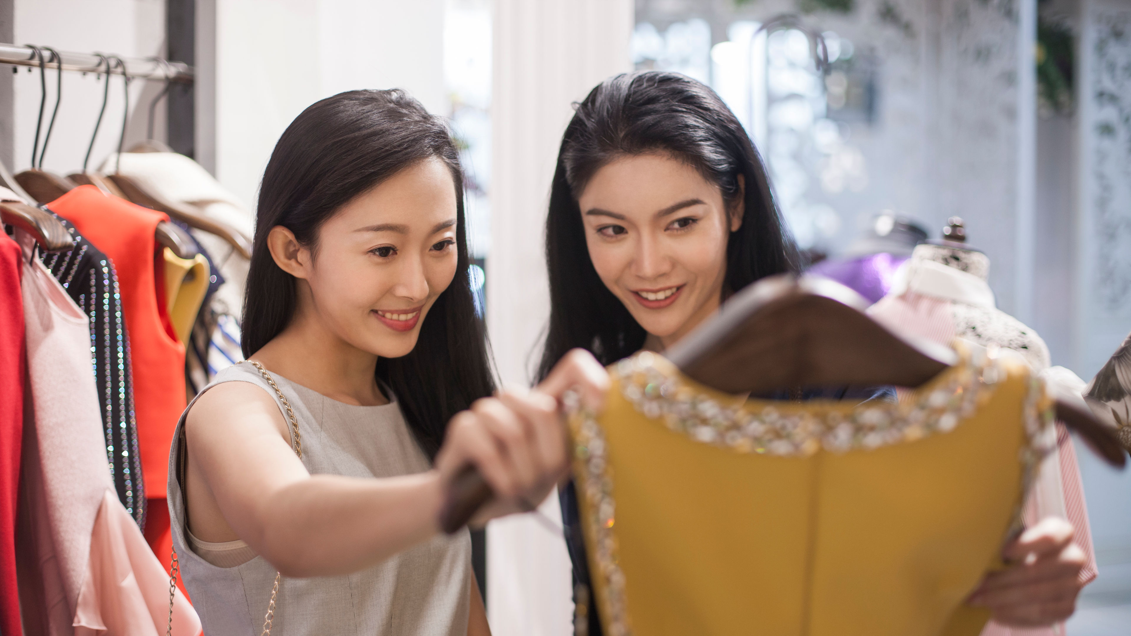 Two best friends enjoy a fun shopping day, exploring trendy clothing styles and sharing fashion tips. 