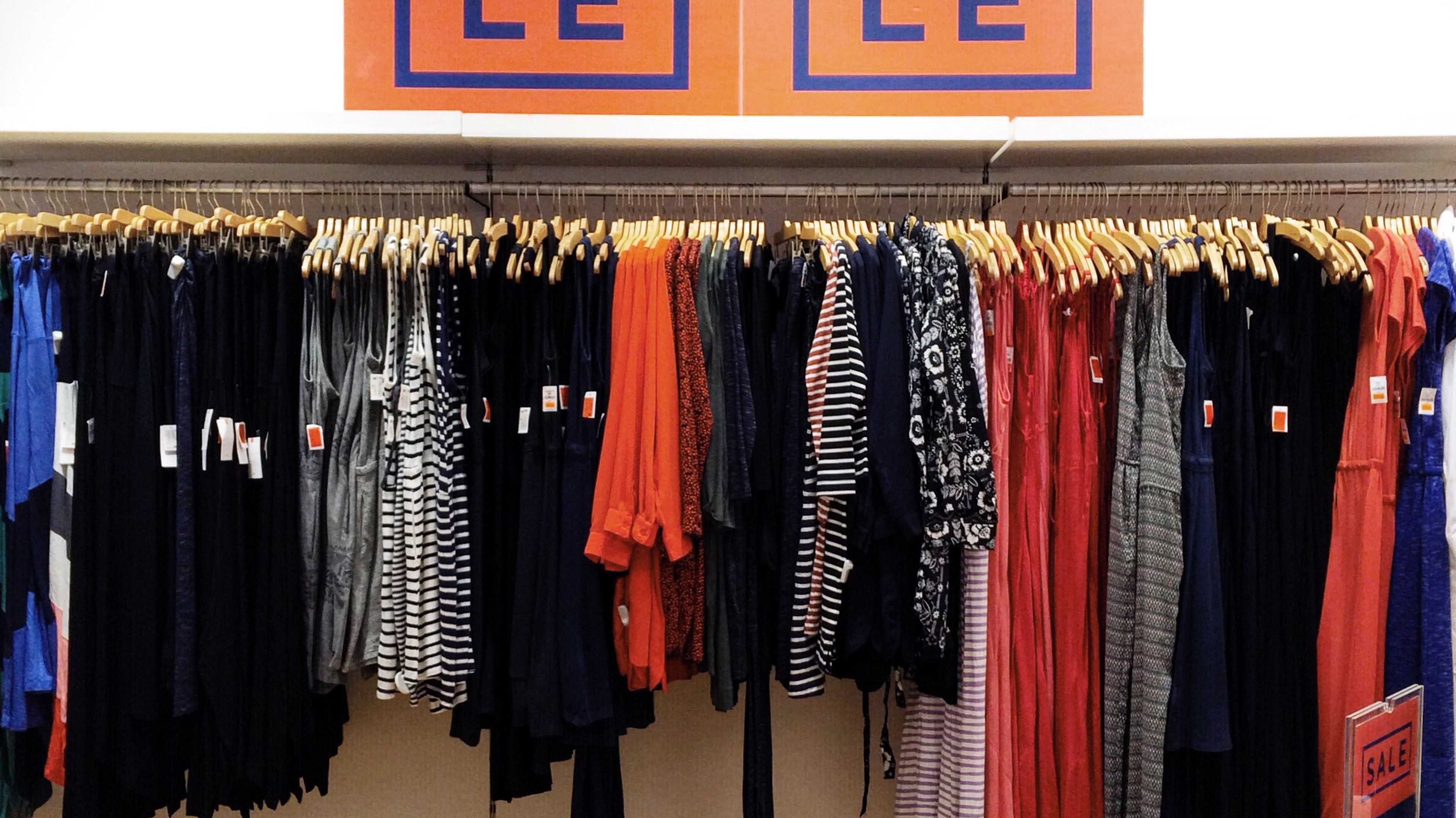 A vibrant "SALE" sign hangs prominently above racks filled with diverse clothing styles 