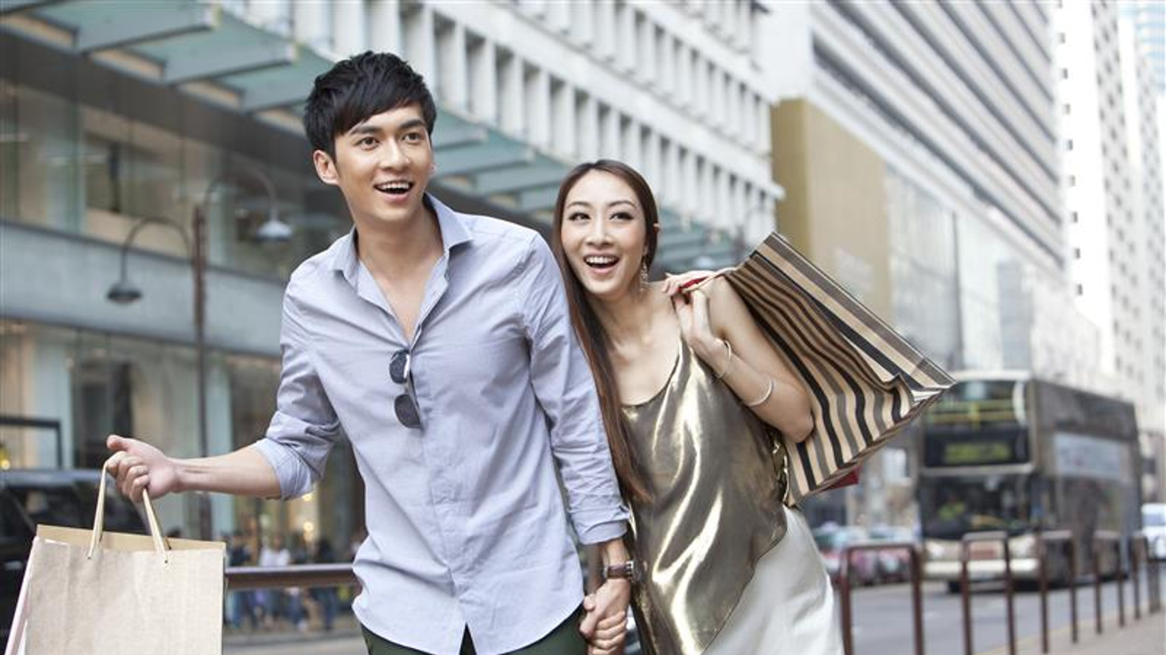 Cheerful young couple with shopping bags walking in the street, Hong Kong 