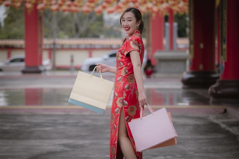 Happy Asian woman wearing red traditional dress holding shopping bags happiness in buy special season on Chinese festival. 