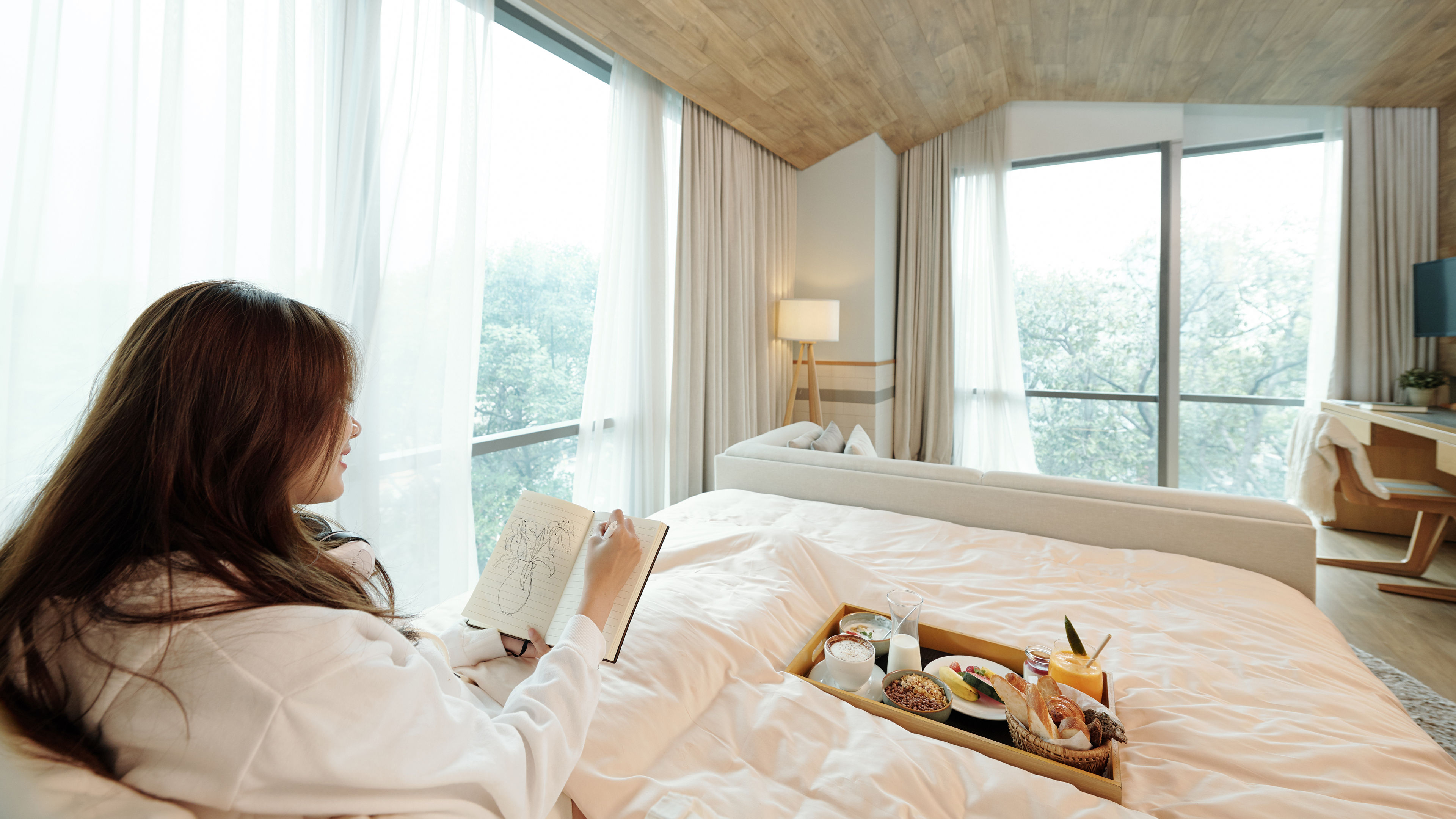 Happy creative young woman spending morning in bed