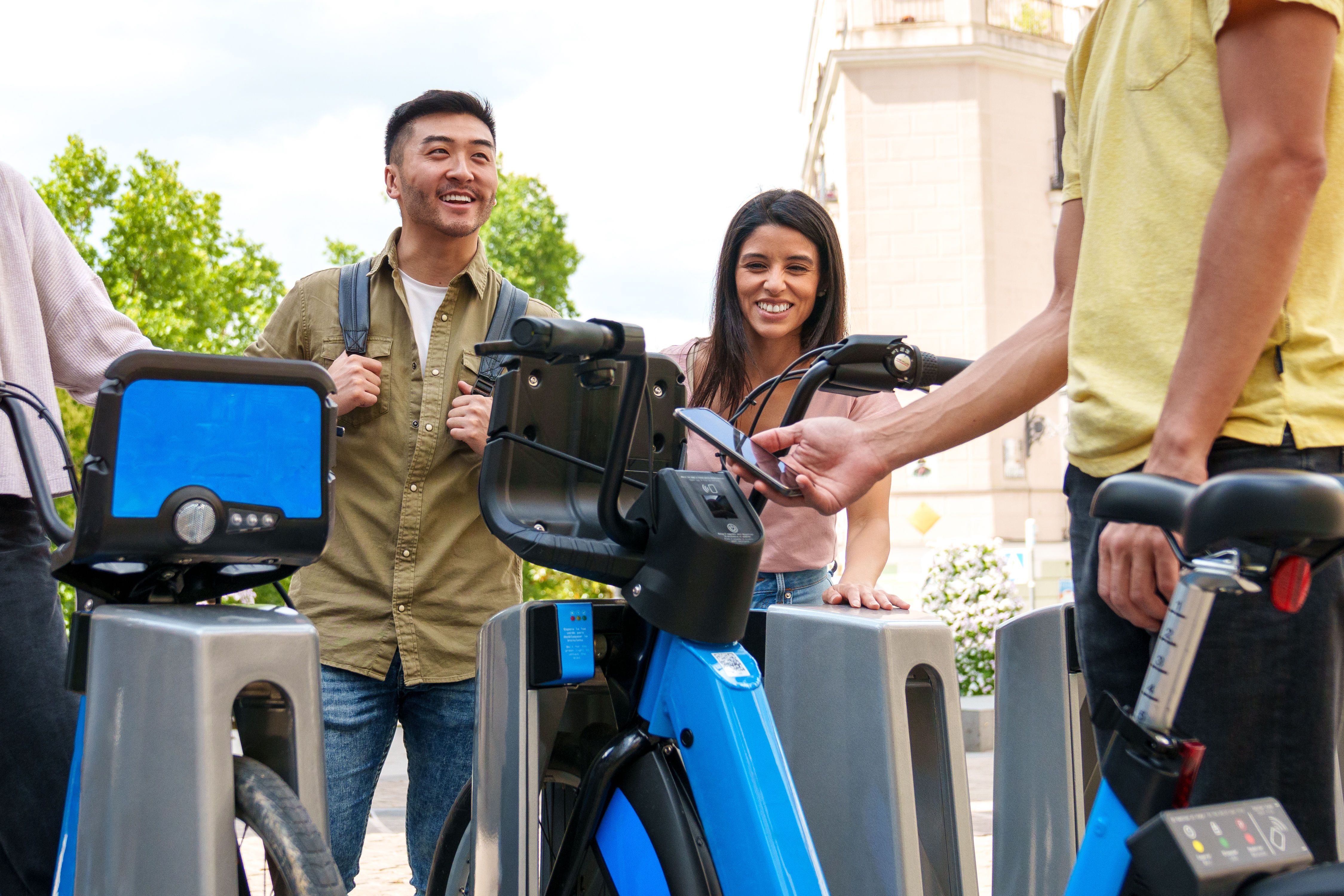Joyful Multiethnic Youths Renting Electric Bikes on Sunny Day.  
