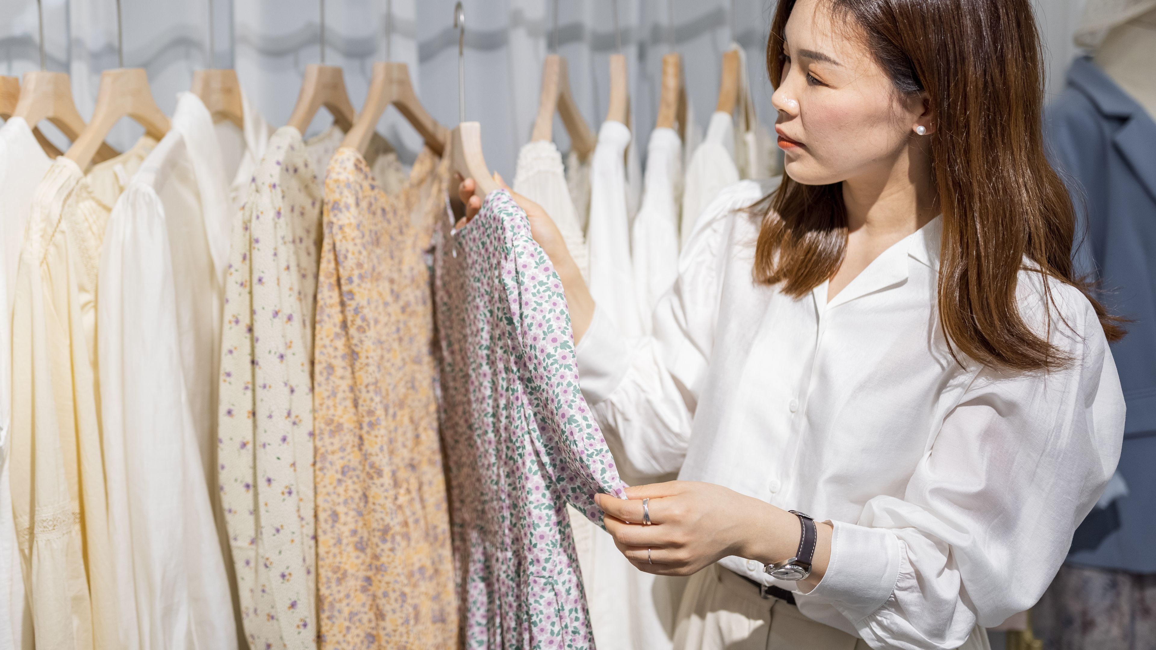 Portrait of happy asian chinese woman entrepreneur working in her modern store with womenswear 