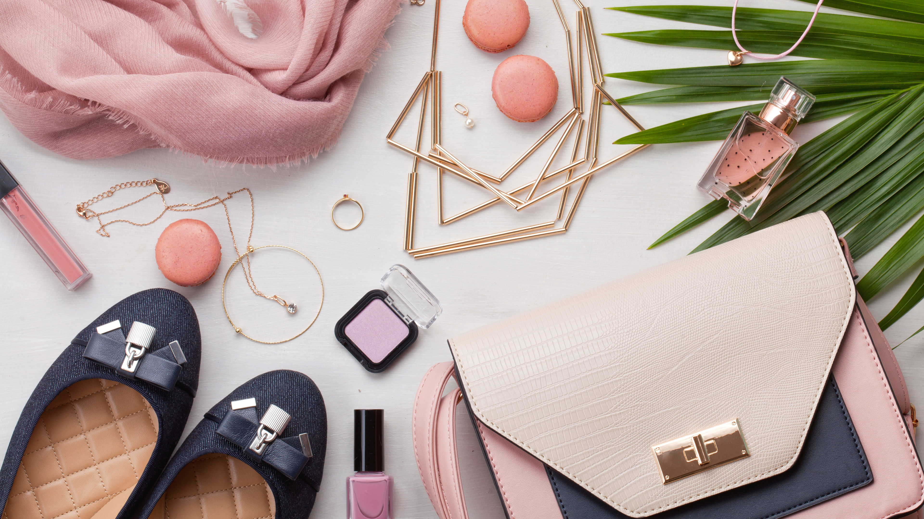 Some fashion accessories like a pair of shoes, jewellery etc on a table. 