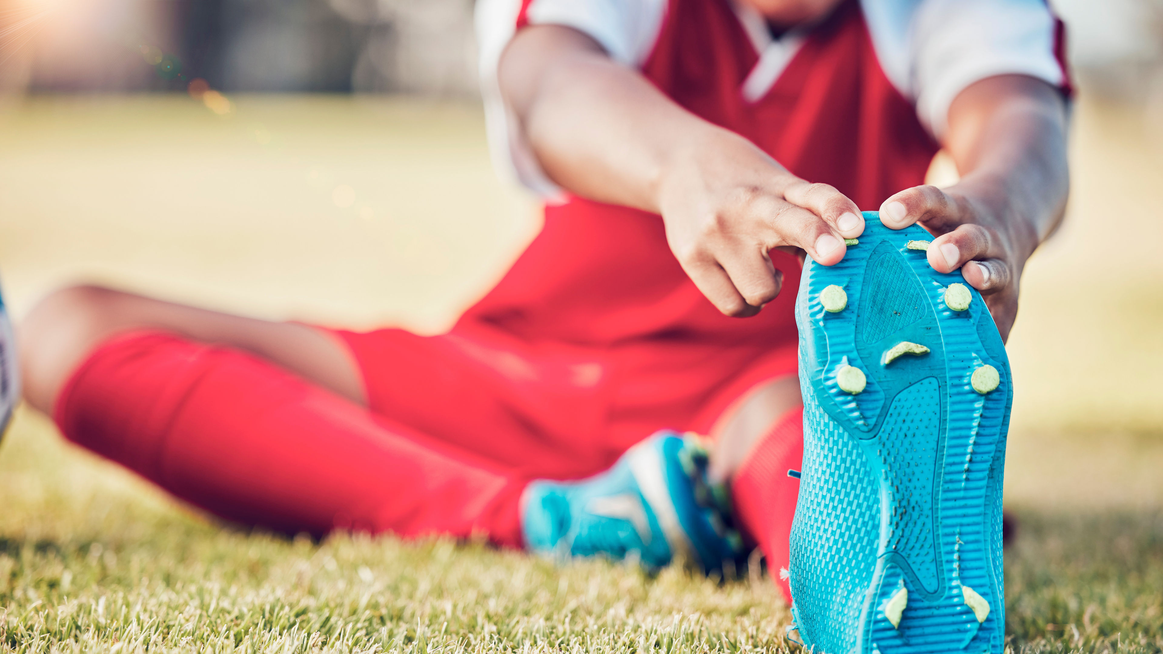 Stretching, a foot and a soccer player on the field for sports training, exercise and leg muscle wellness