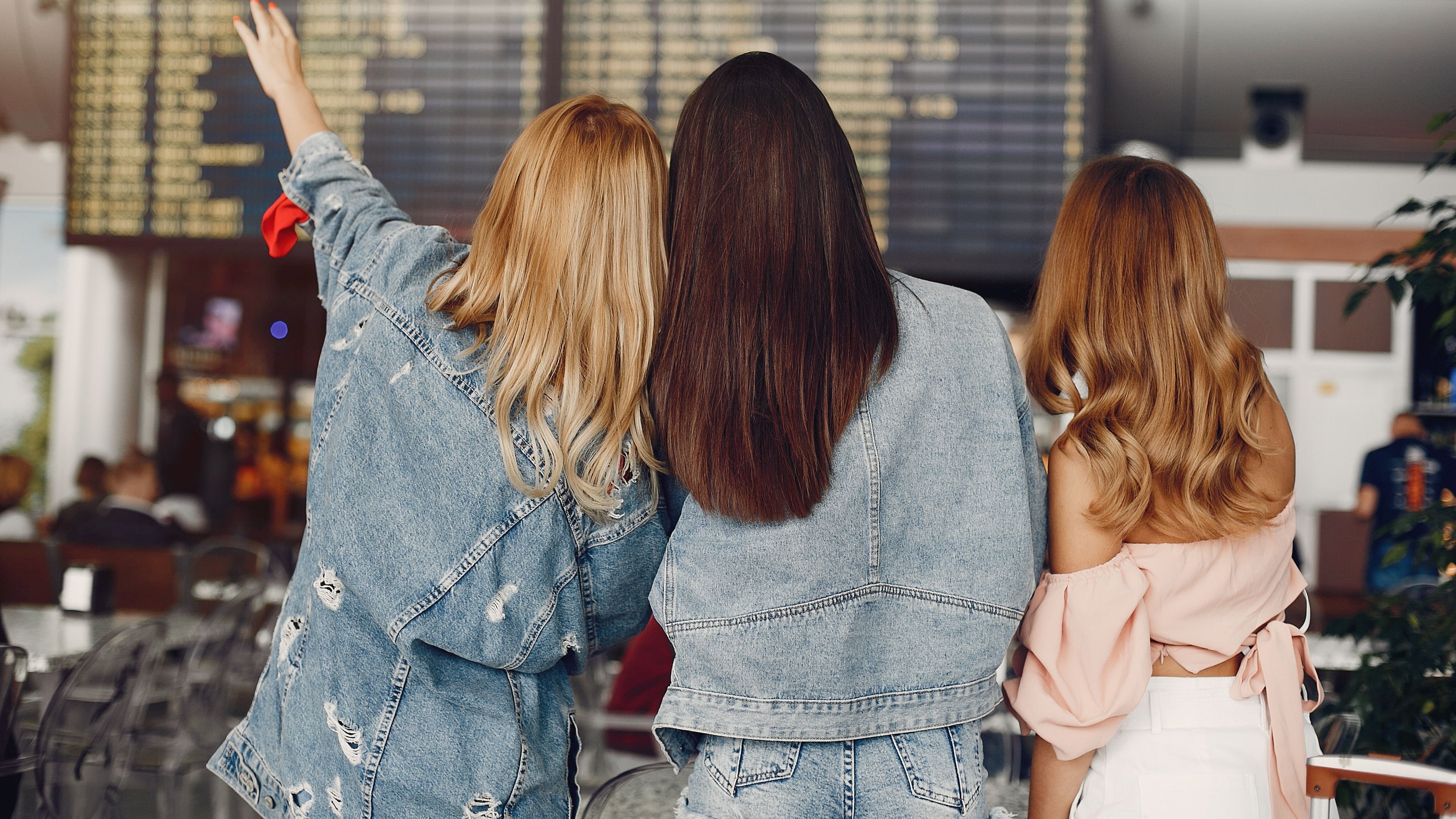 Three young women looking at the flight information display