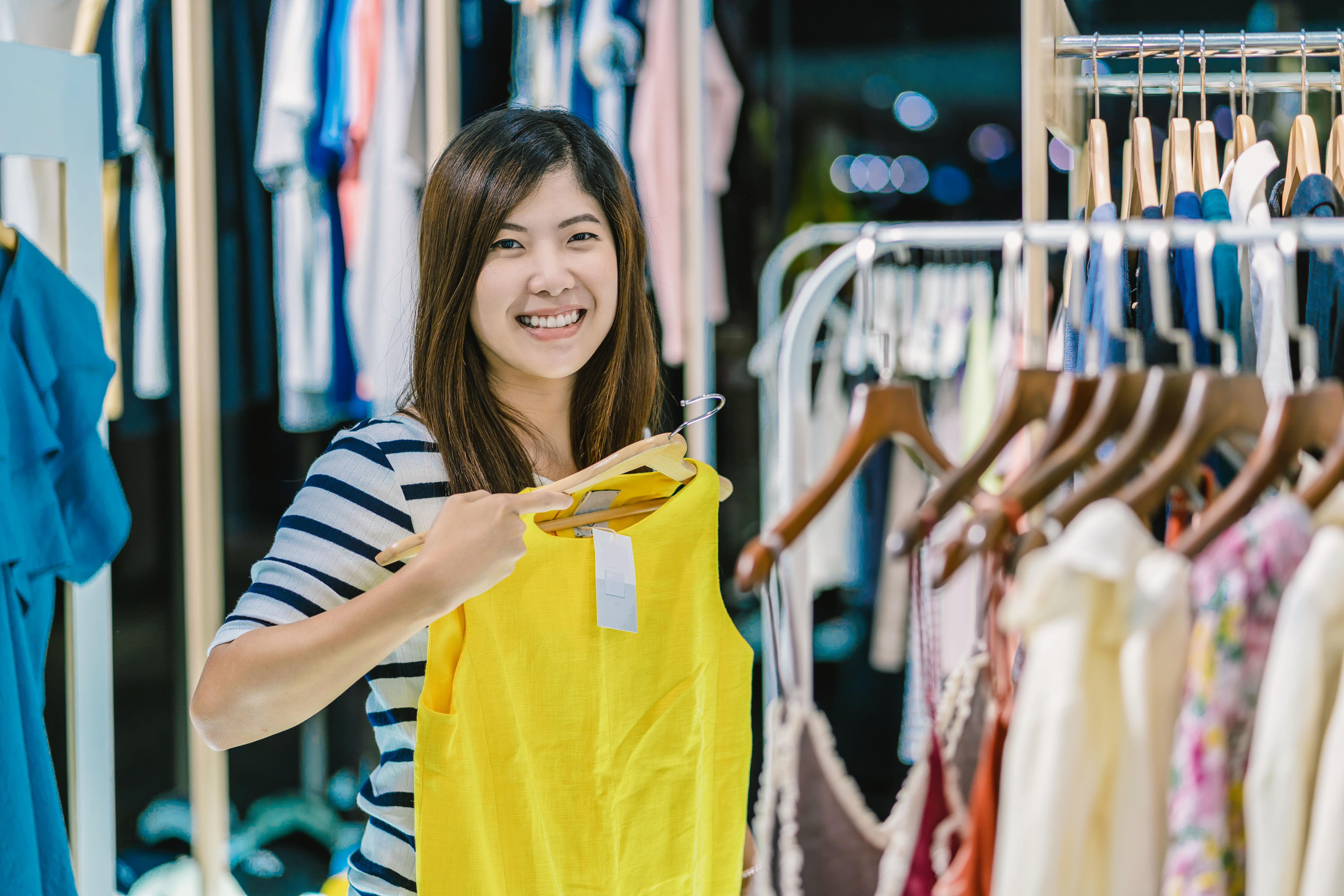 A smiling woman holding yellow dress on her hand 